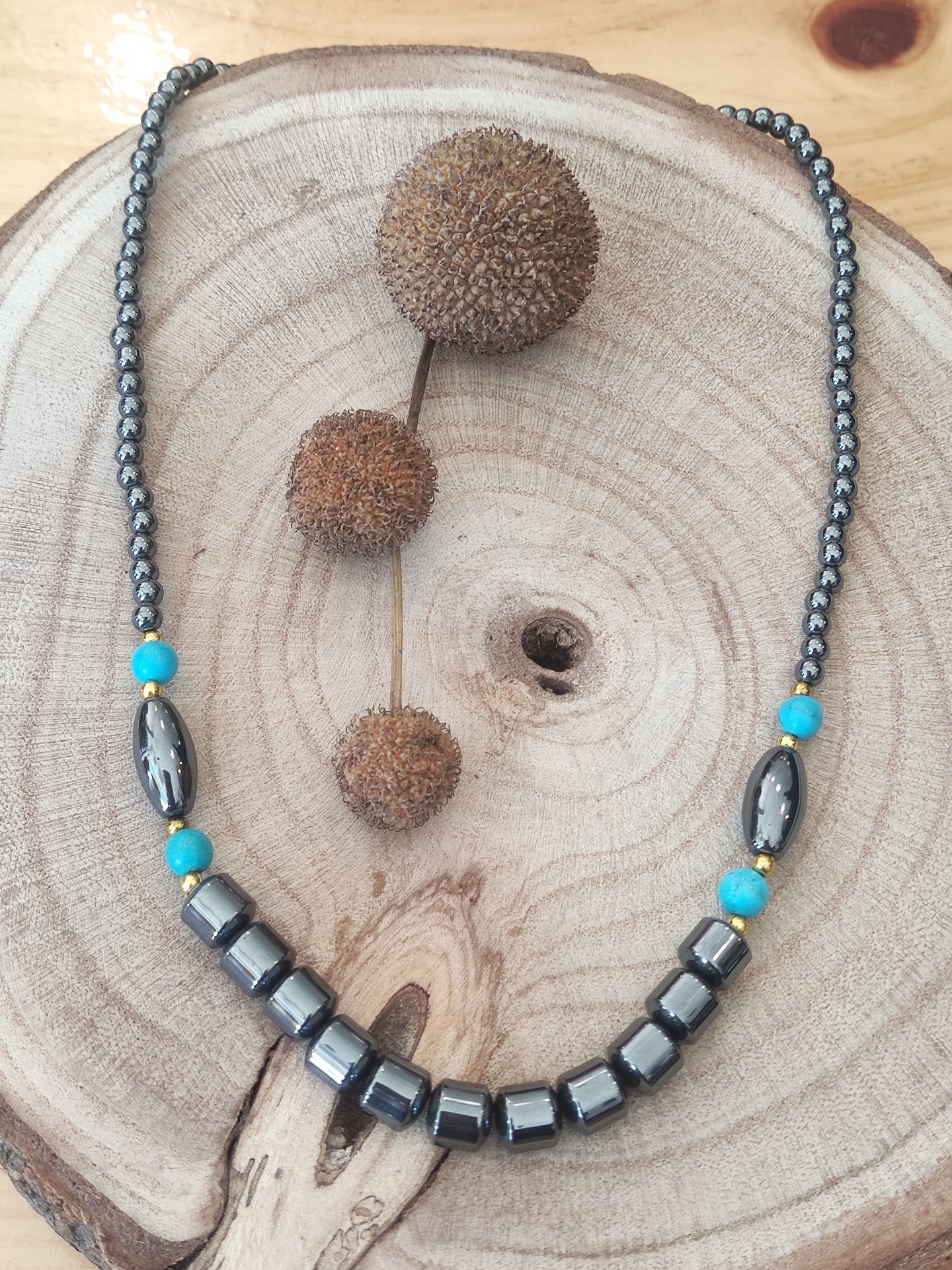 Colar com contas negras e contas azuis turquesa sobre base de madeira clara