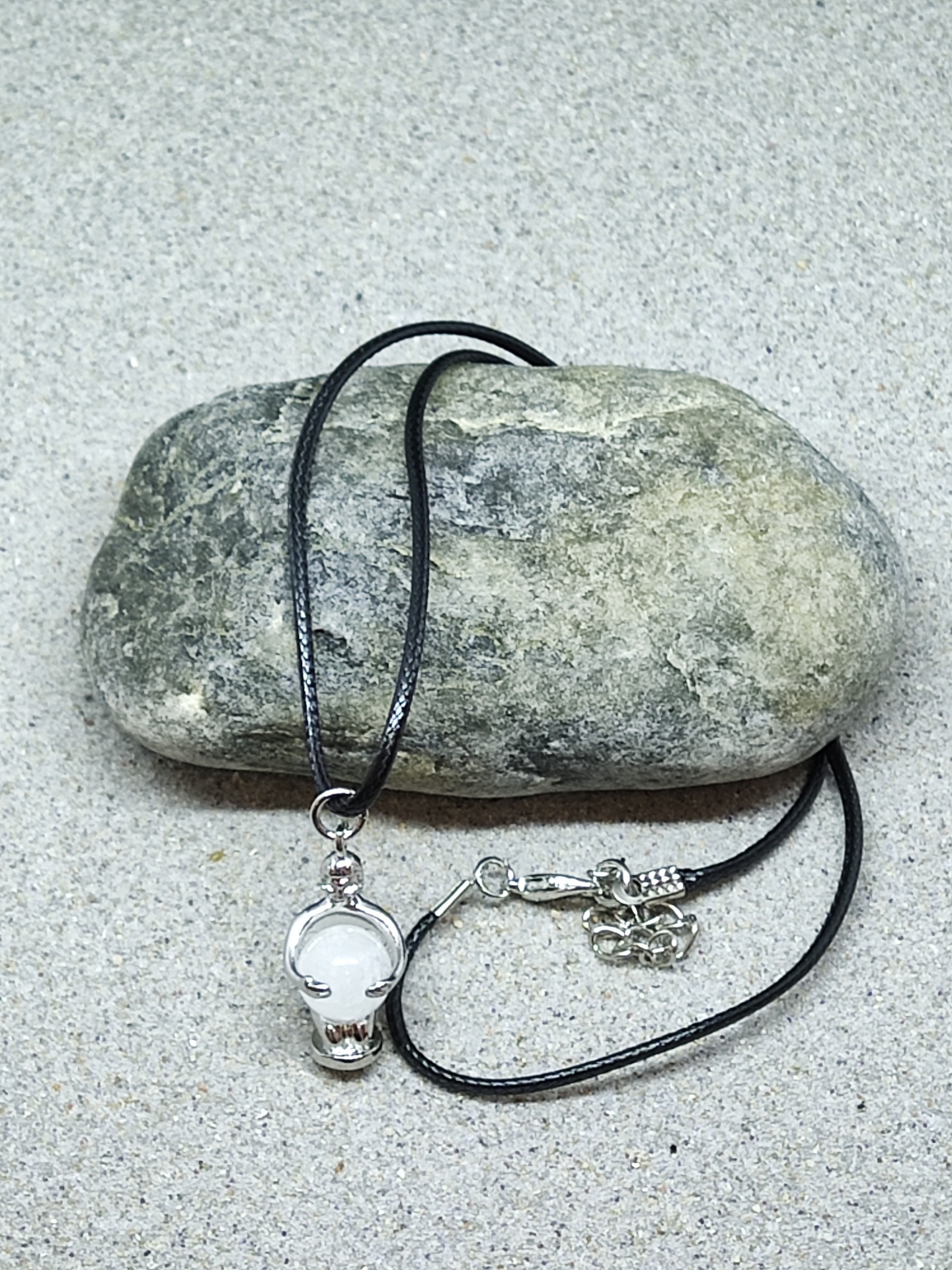 Colar com pendente de caveira prateada sobre pedra cinzenta