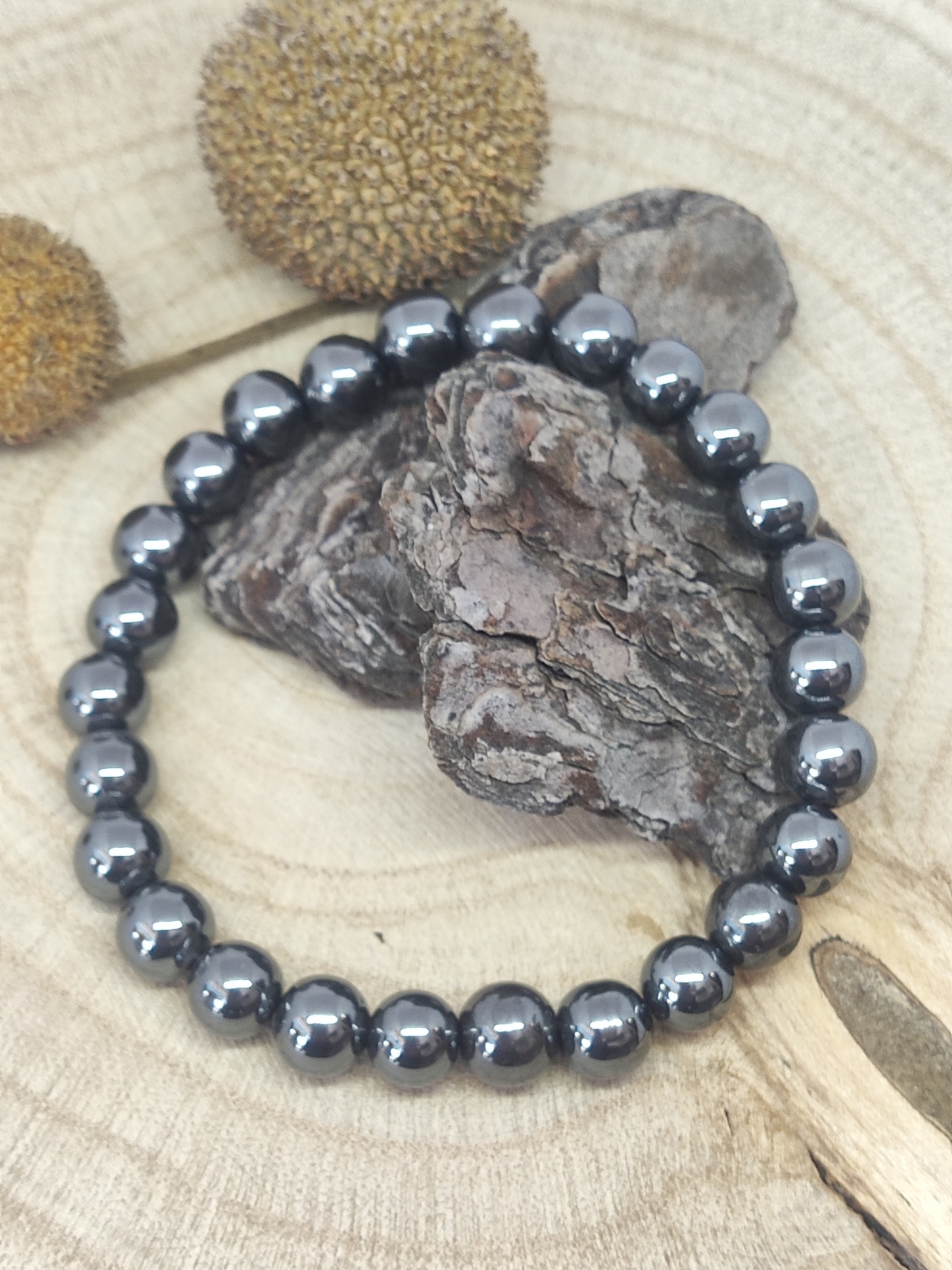 Pulseira de contas metálicas prateadas sobre suporte de madeira clara