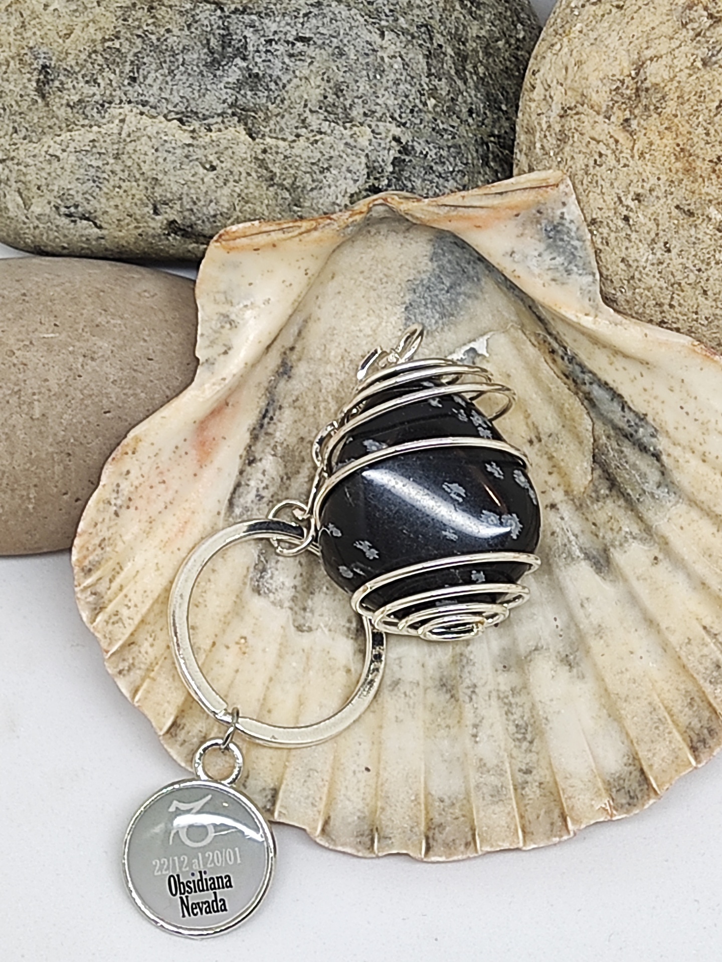 Chaveiro com esfera preta e pendente metálico sobre concha e pedras