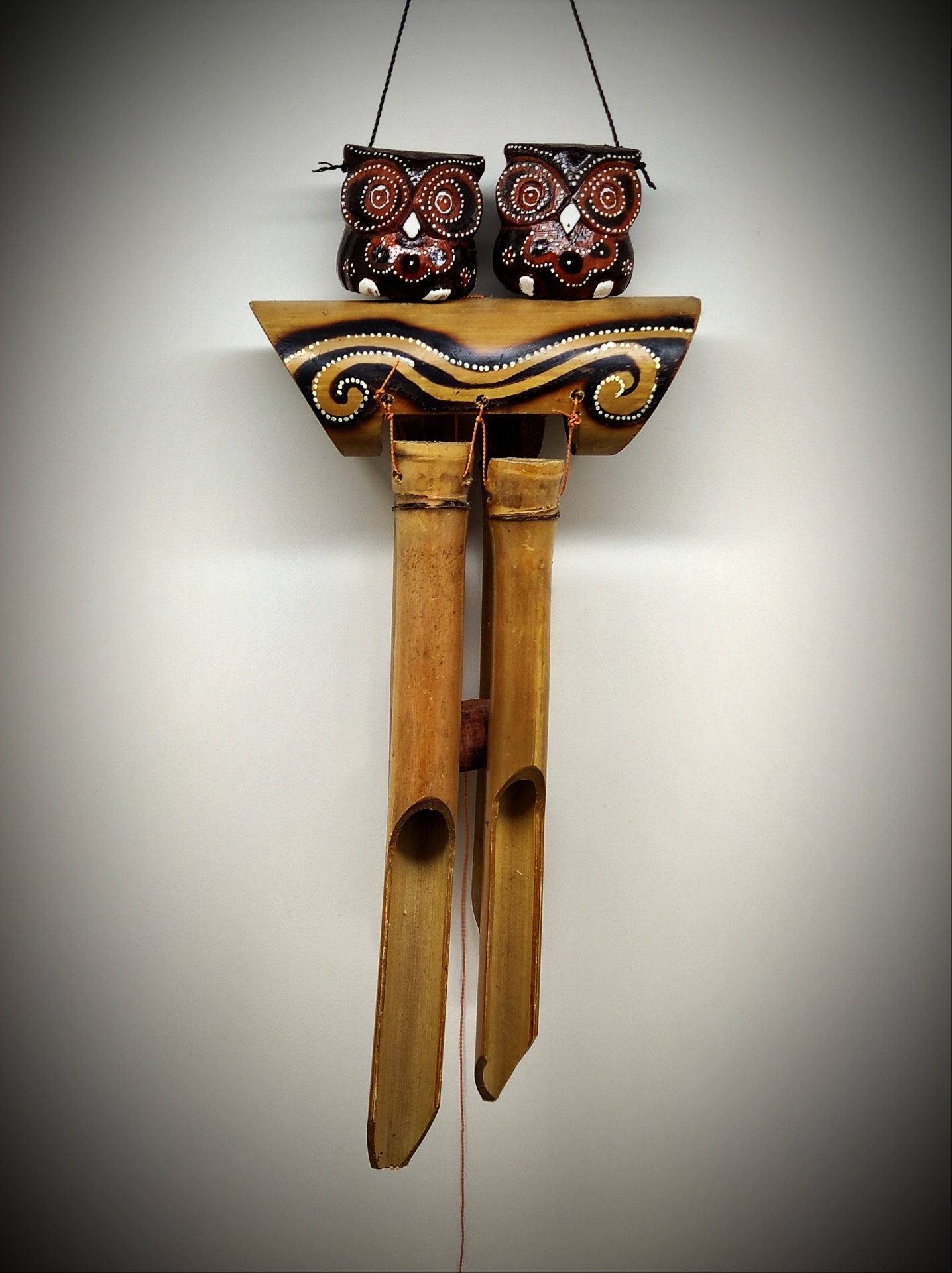 Peça decorativa pendurada com duas corujas em madeira e tubos de bambu