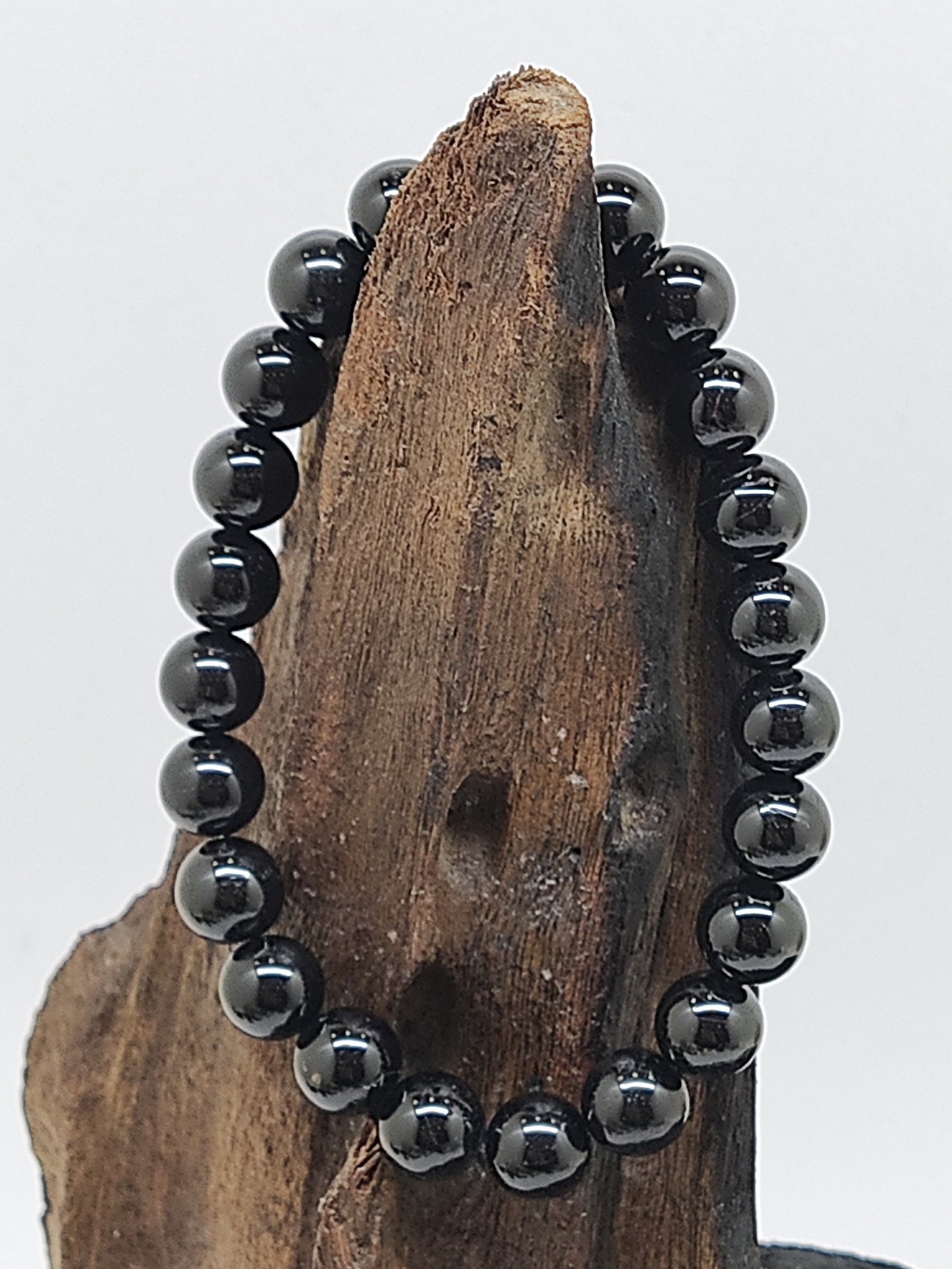 Pulseira de esferas pretas brilhantes sobre pedaço de madeira