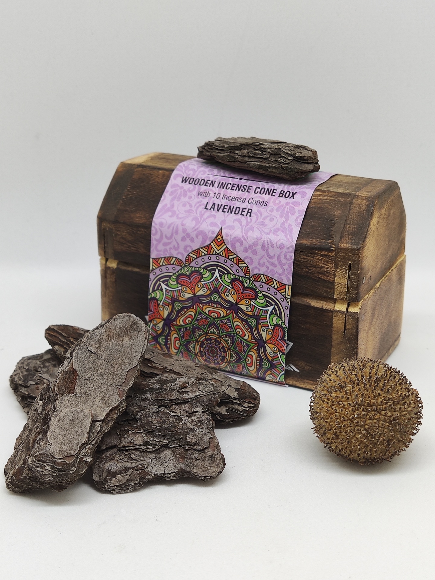 Caixa de incenso em madeira com etiqueta roxa e cascas de madeira ao redor