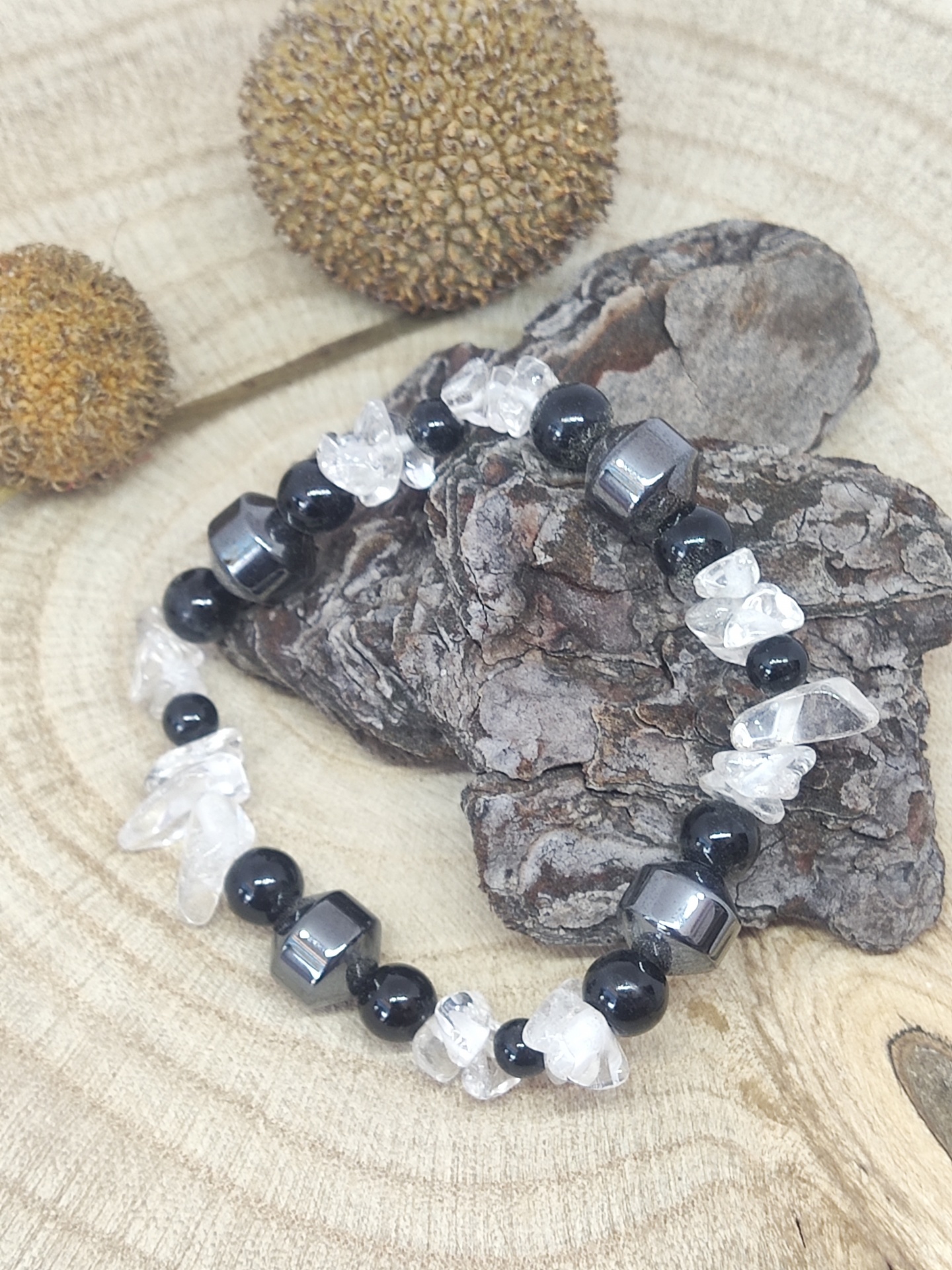 Pulseira de pedras pretas, transparentes e cinzentas sobre casca de árvore