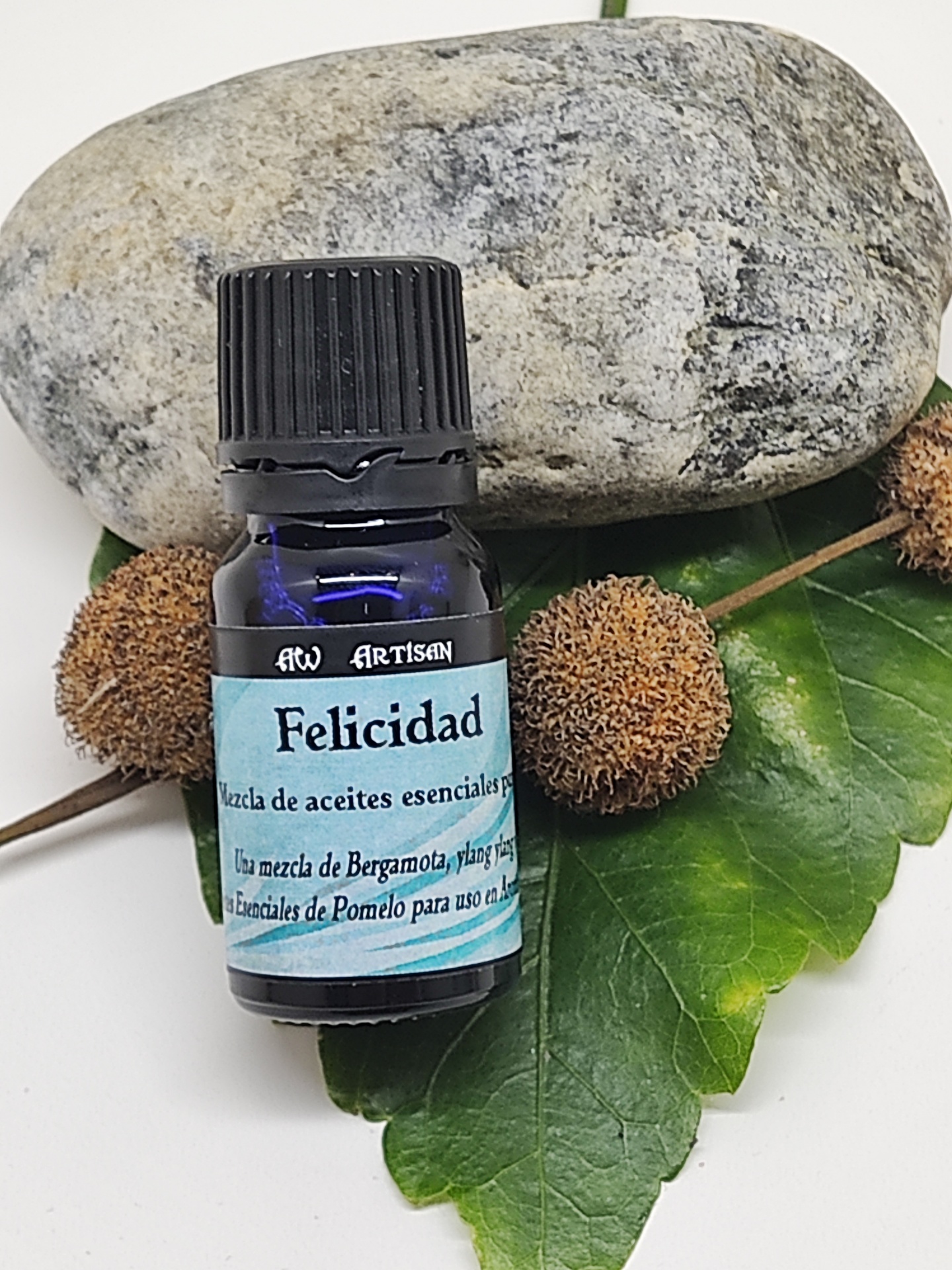 Frasco de óleo essencial azul com rótulo em folha verde, pedra cinza e bolas castanhas