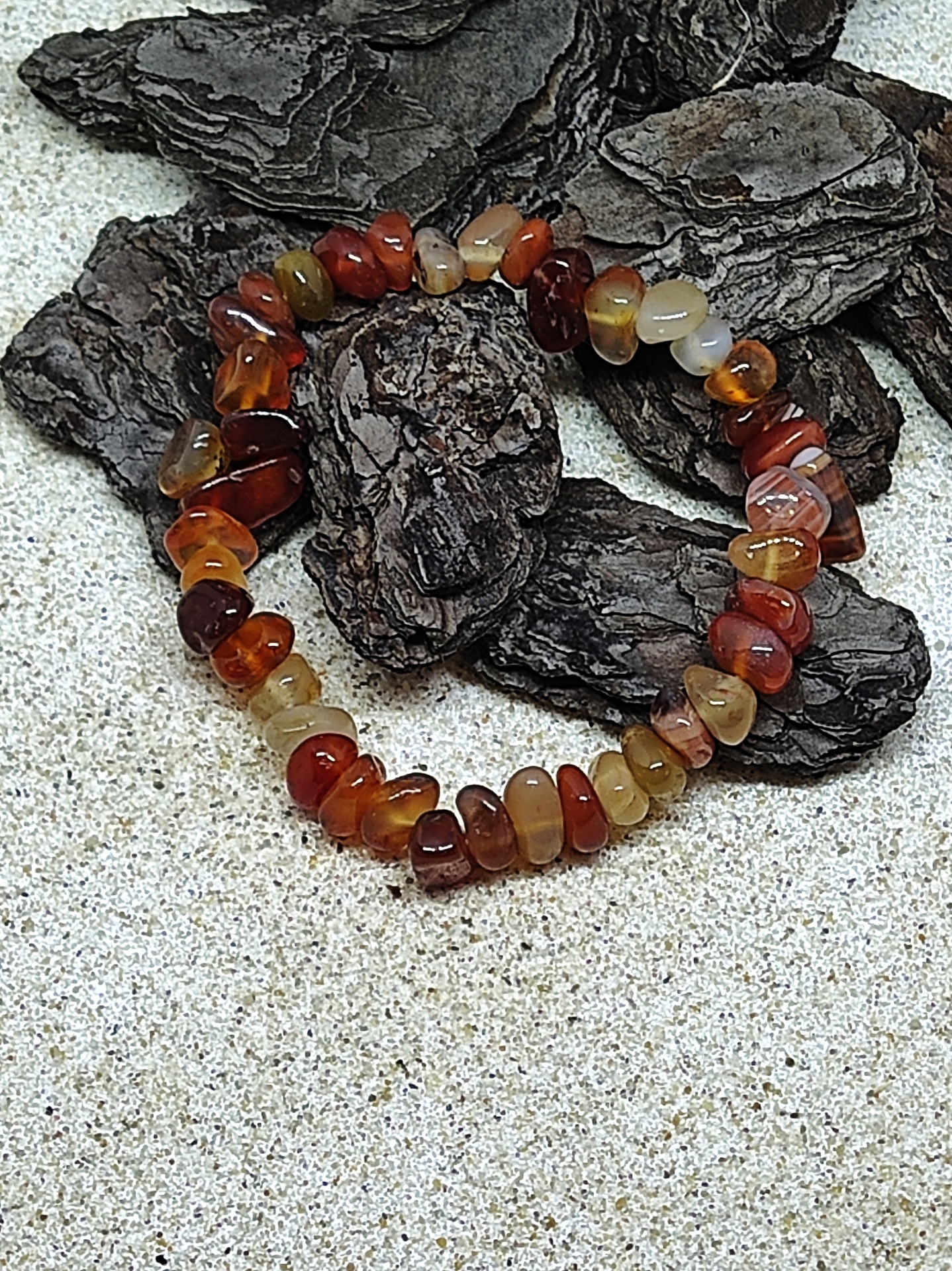 Pulseira de pedras naturais castanhas sobre casca de árvore