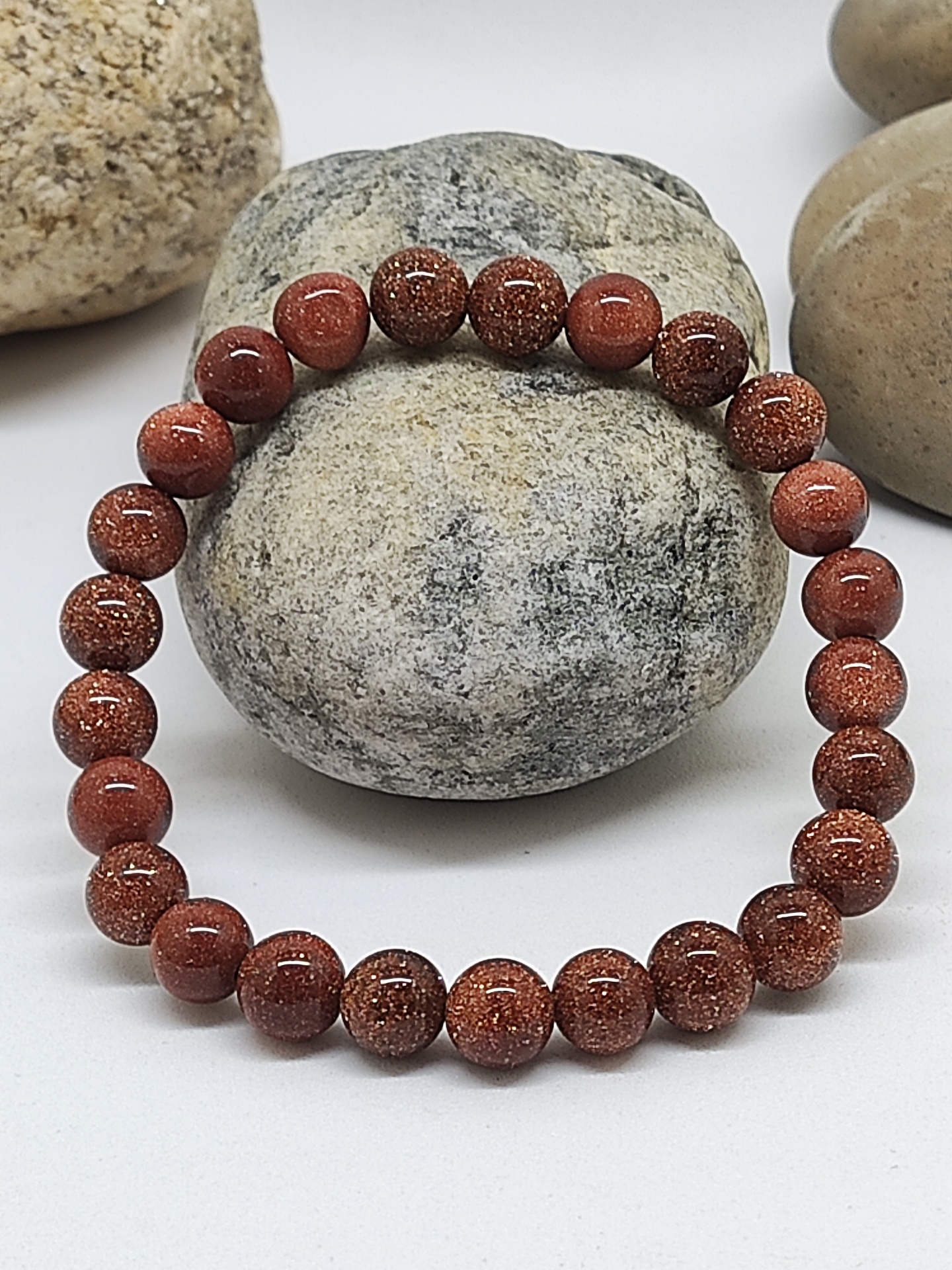 Pulseira de contas castanhas brilhantes sobre pedras naturais cinzentas e bege