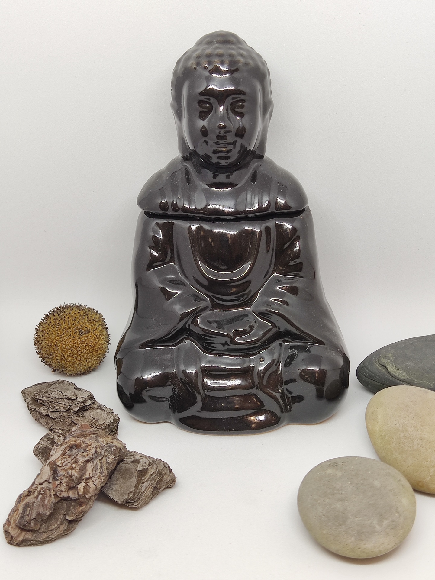 Figura de Buda em cerâmica castanha brilhante com pedras e casca de árvore sobre fundo branco
