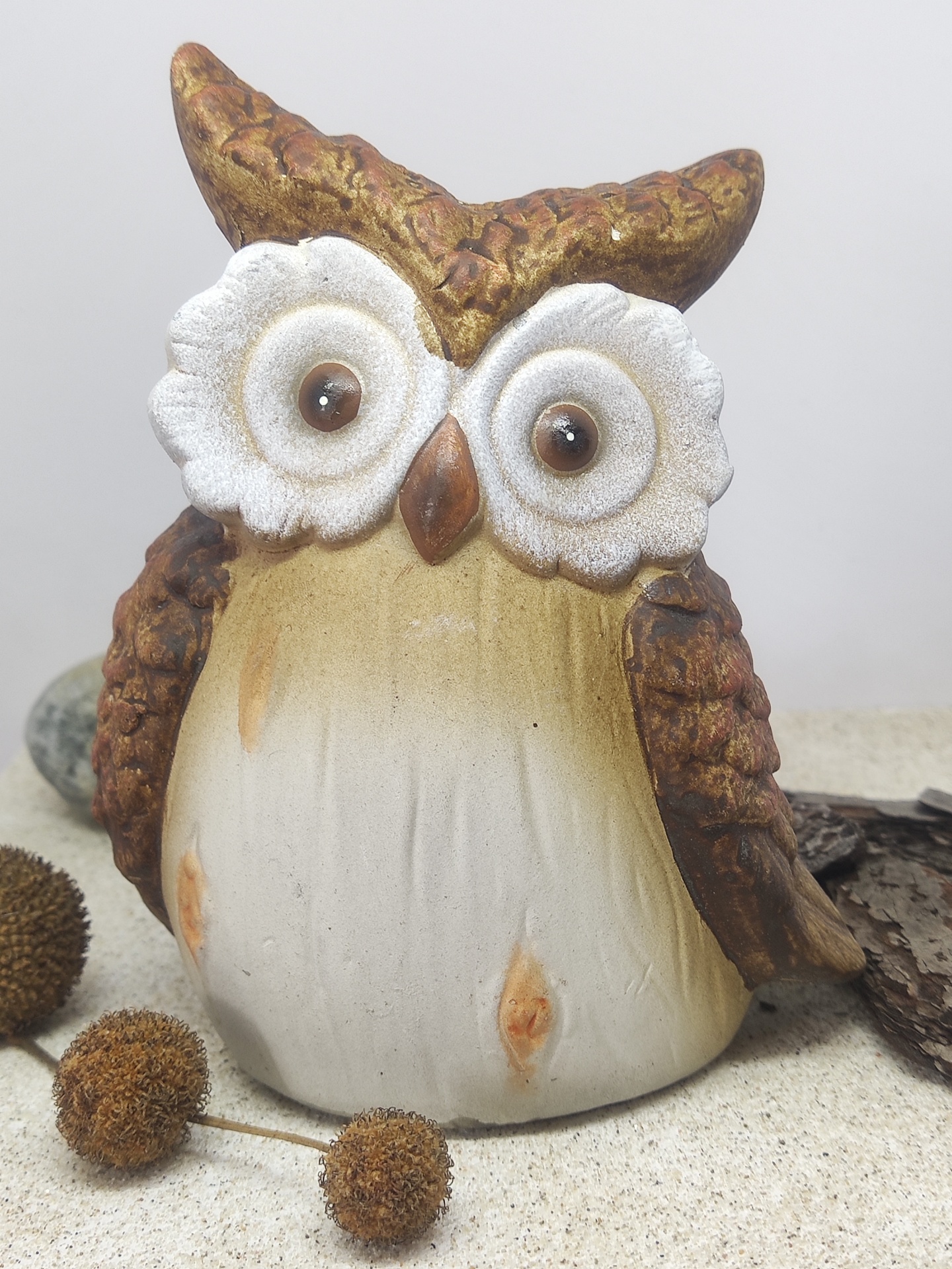 Figura decorativa de coruja em cerâmica com olhos grandes e cores castanho, branco e bege