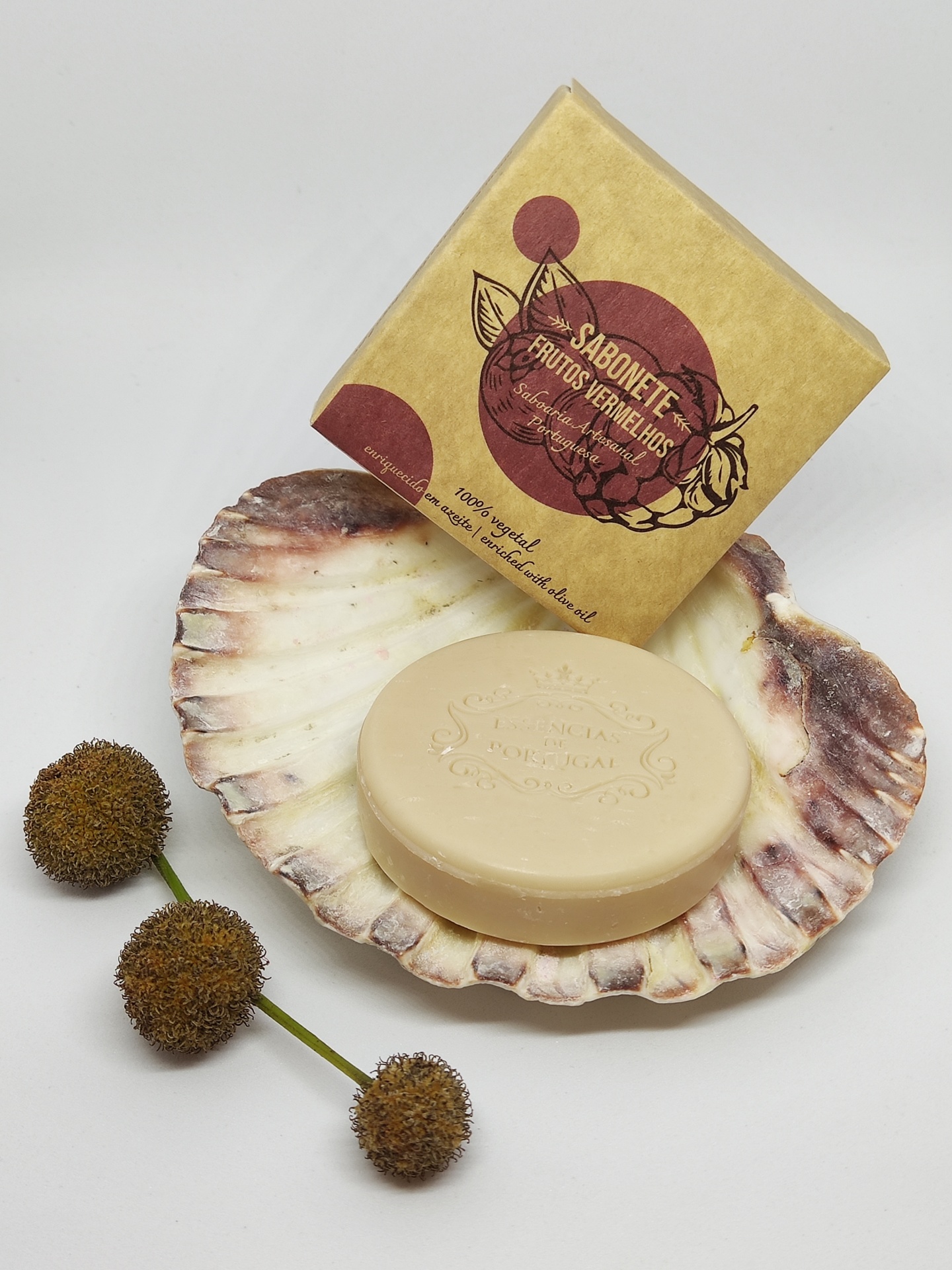 Sabonete redondo bege numa concha com embalagem de papel castanho e flores secas