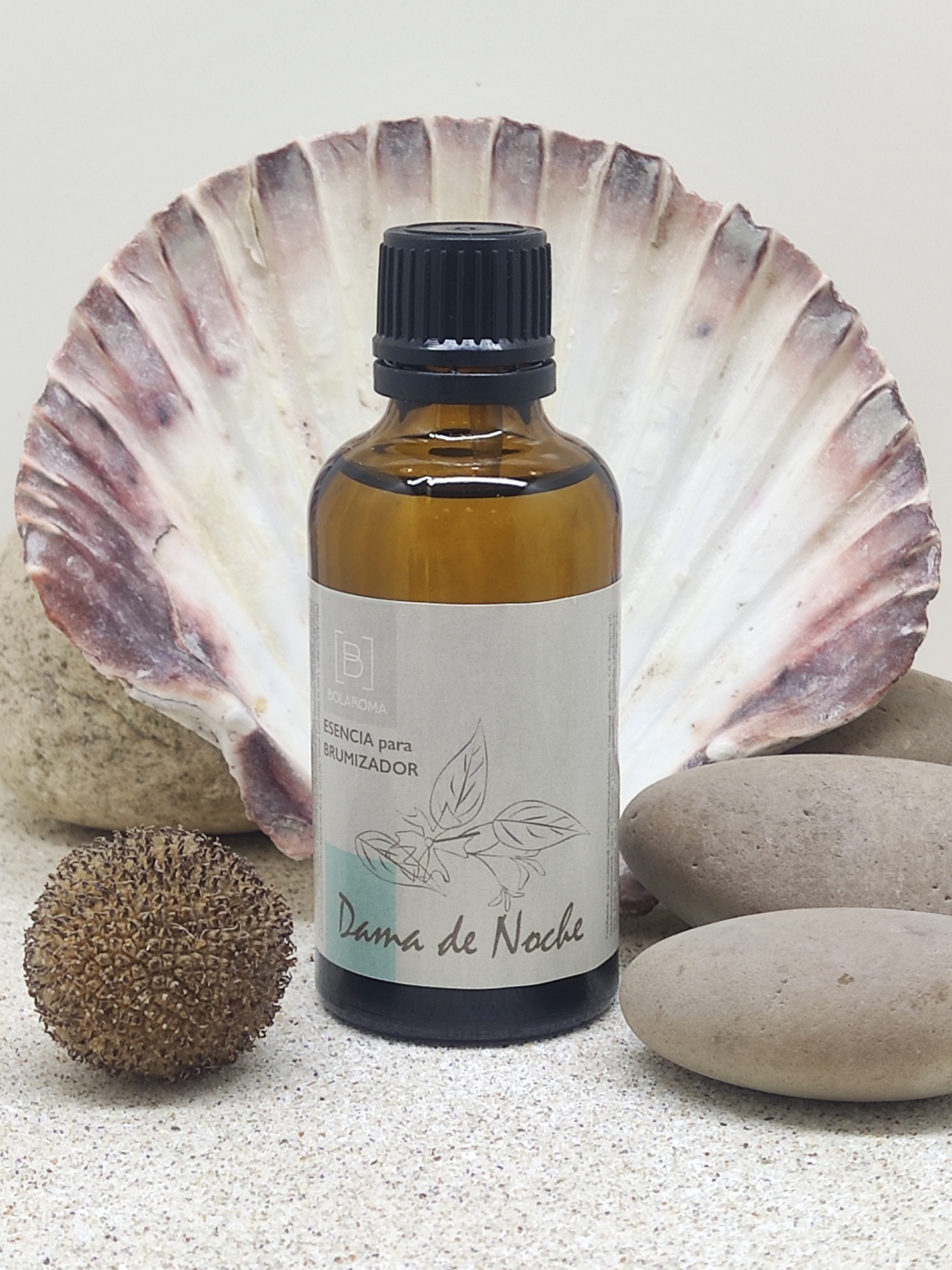 Frasco âmbar de essência para umidificador com concha e pedras ao fundo