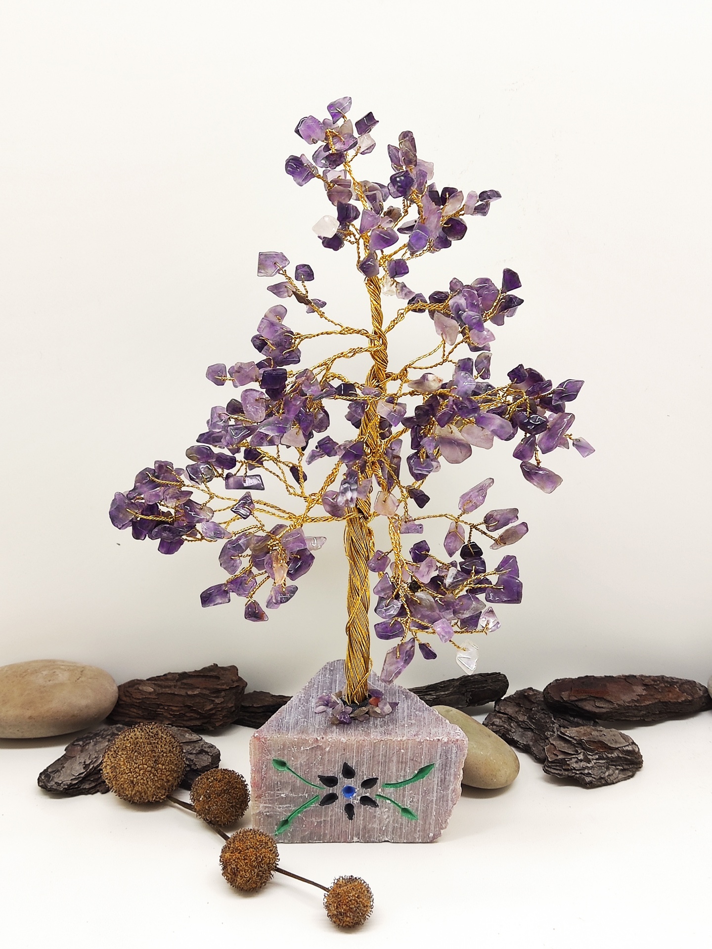 Árvore decorativa de arame com pedras ametista sobre base de pedra rosa com padrão
