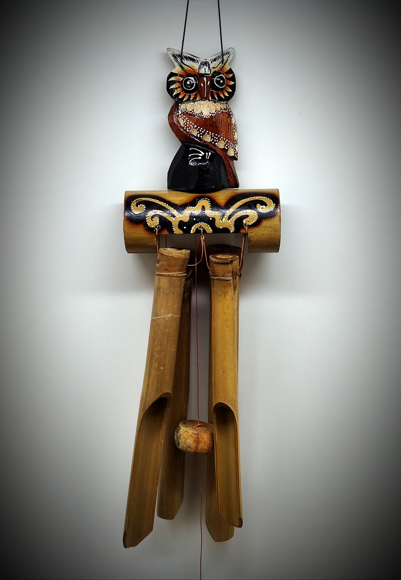Cata-vento decorativo de madeira com figura de coruja e tubos de bambu suspensos