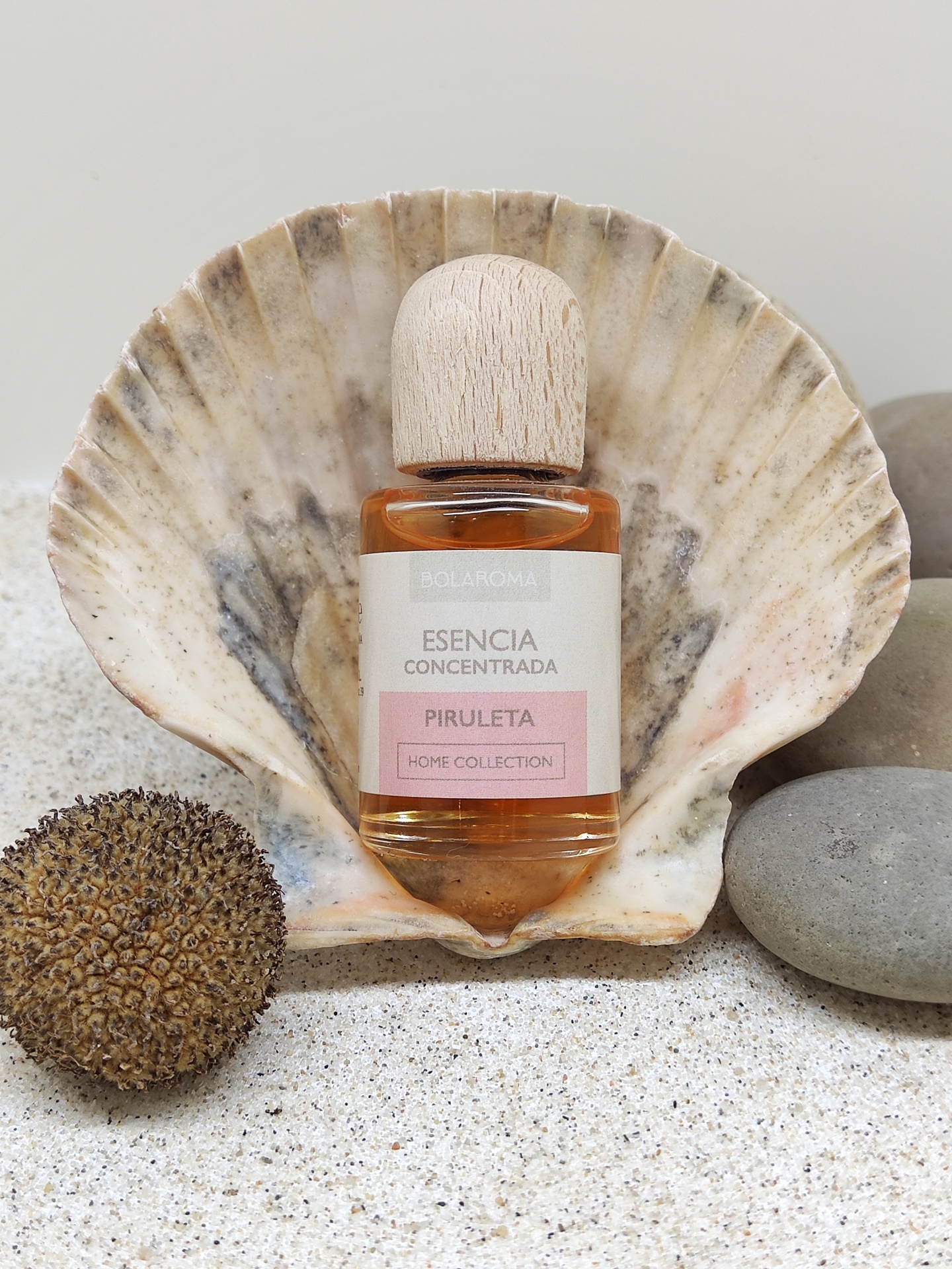 Frasco de essência concentrada PIrULETA dentro de concha sobre areia com pedras