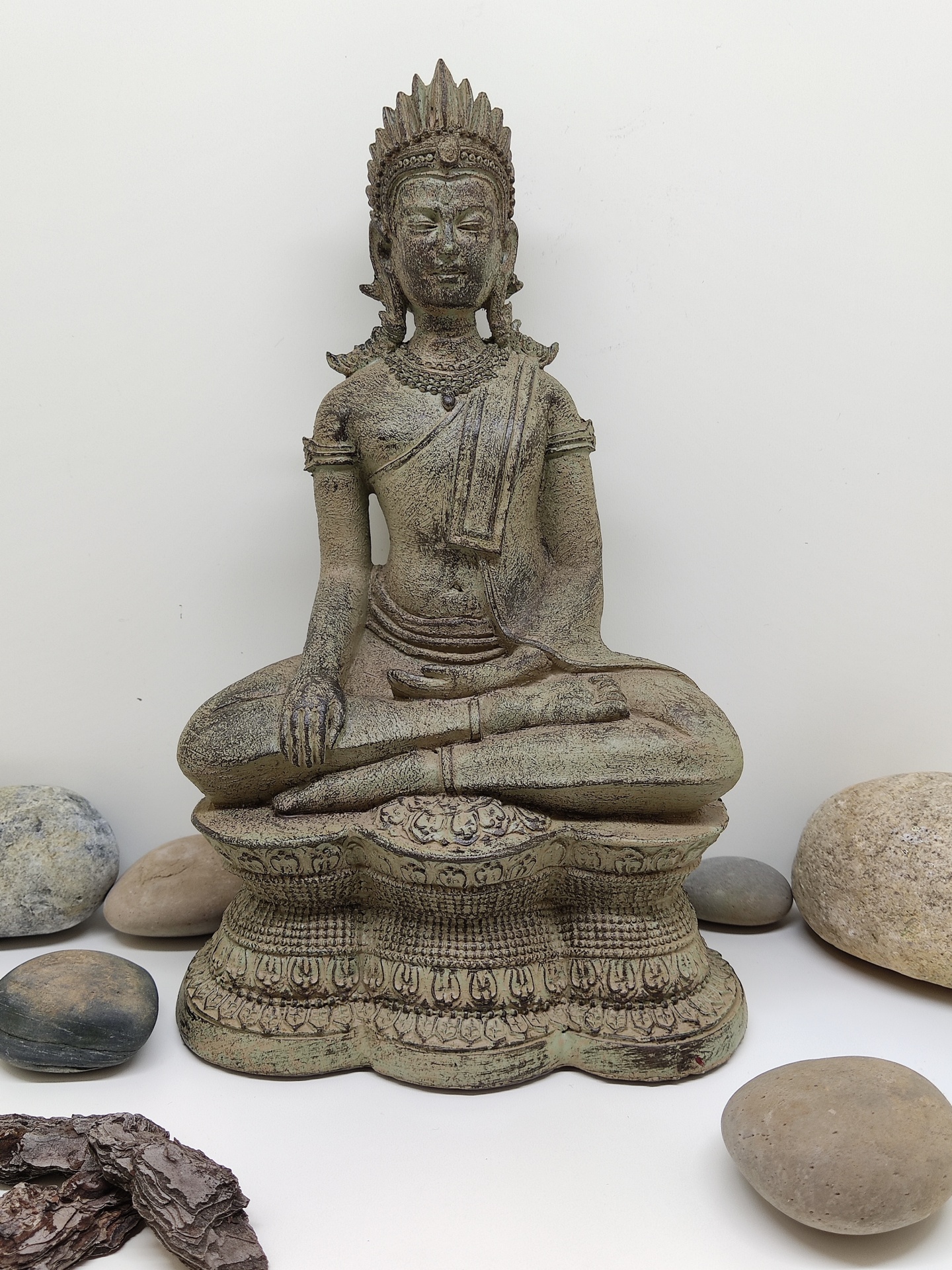 Estátua de Buda feita em material envelhecido rodeada por pedras naturais