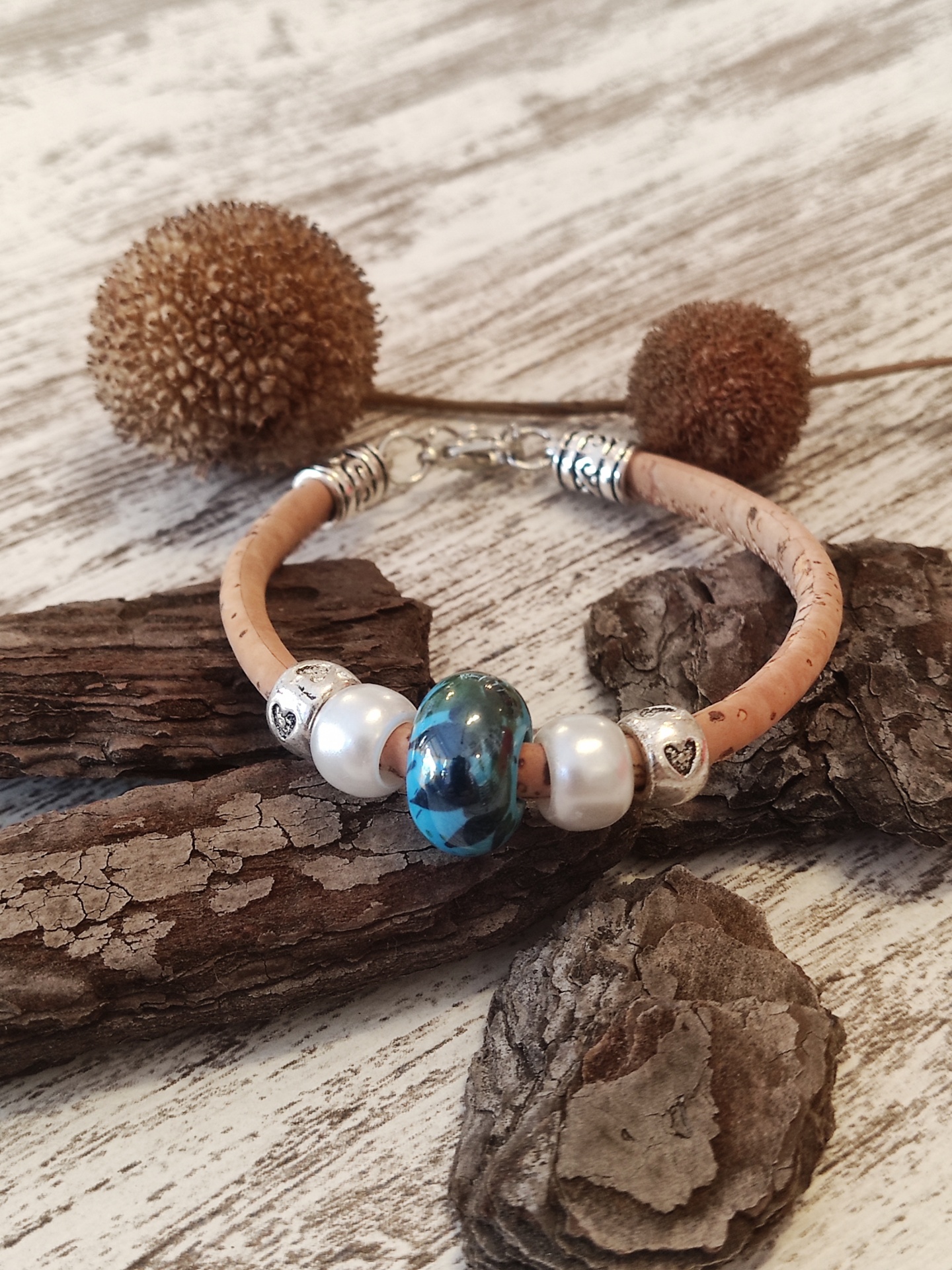 Pulseira com cordão bege e contas decorativas sobre madeira rústica