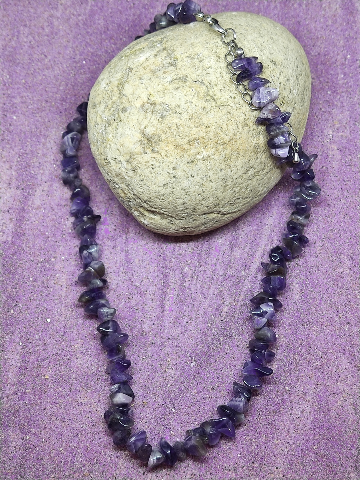Colar de contas de pedra roxa em areia roxa com pedra cinza ao fundo
