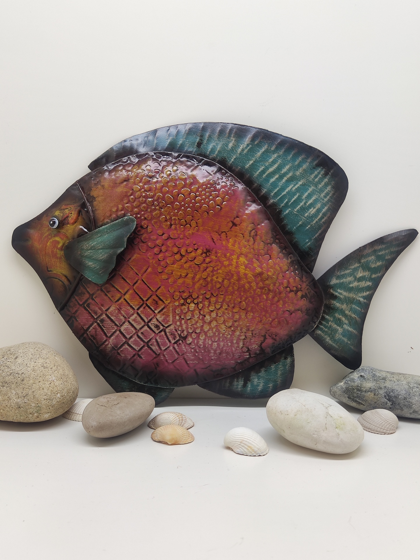 Peixe decorativo em metal pintado com textura em relevo e pedras e conchas naturais