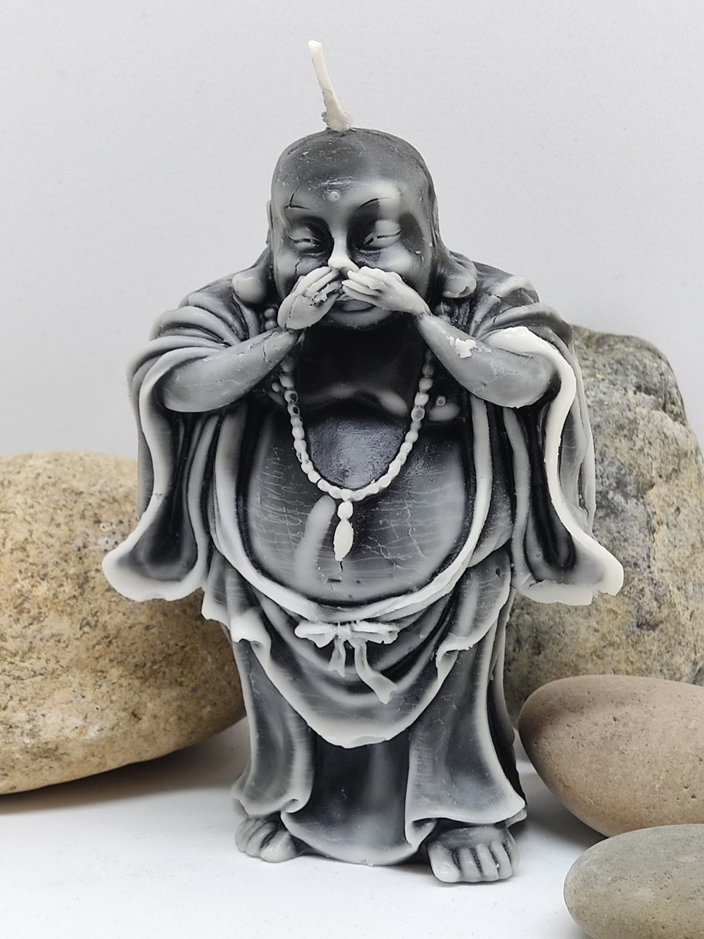 Vela decorativa em forma de Buda cinzento a tapar a boca