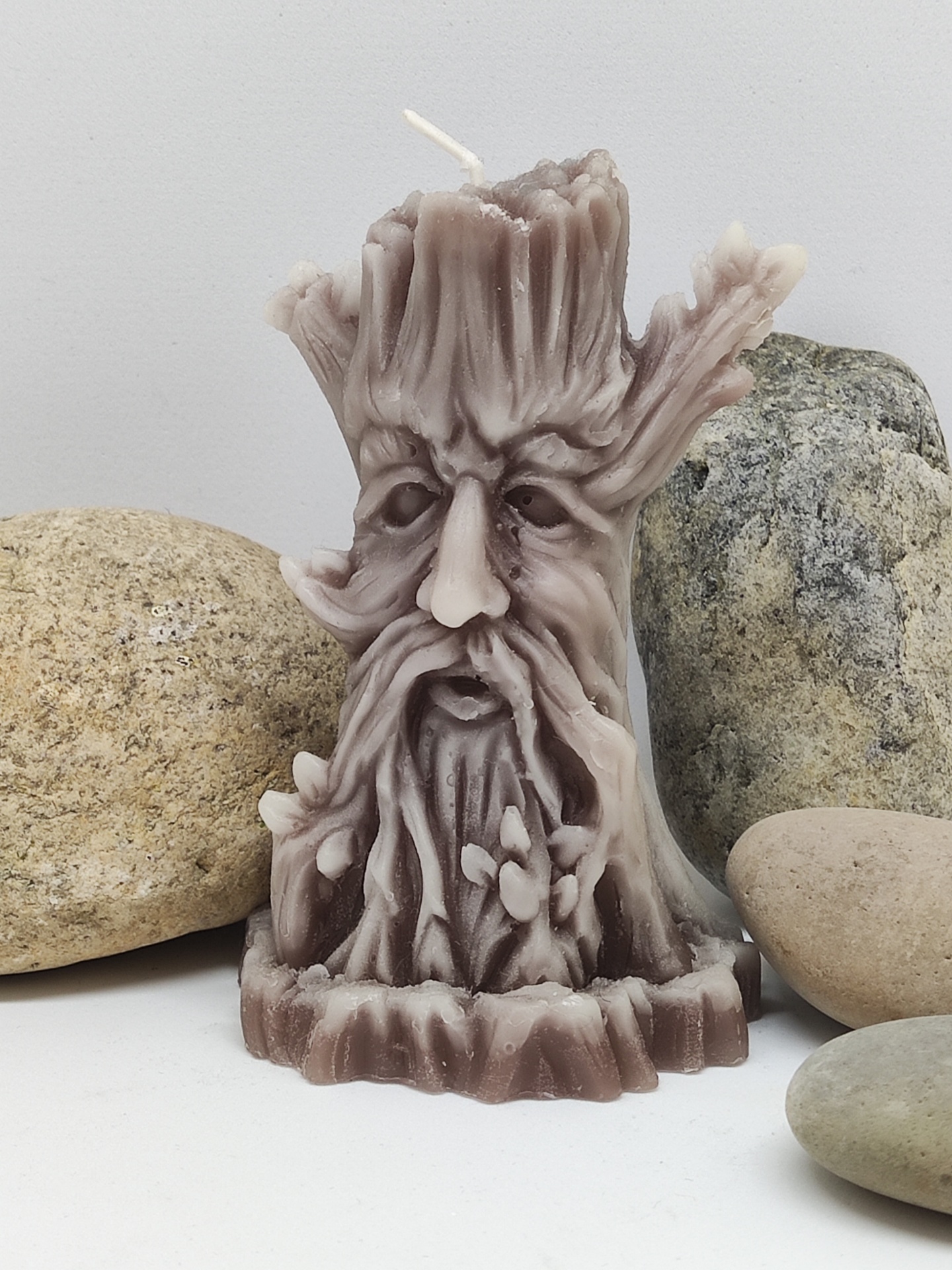 Vela em forma de árvore com rosto, com pedras ao redor