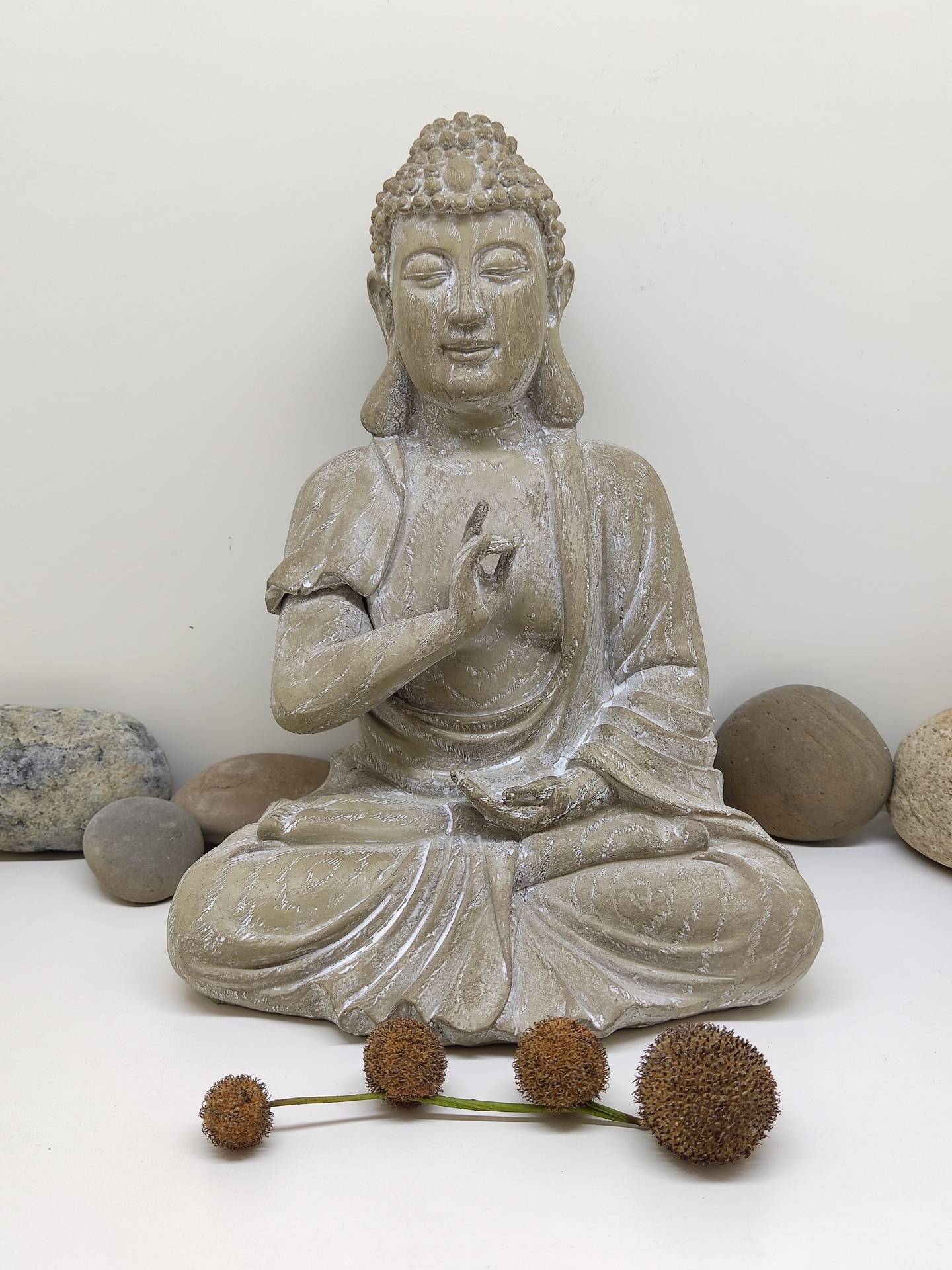 Estátua de Buda em pedra com pedras e flores secas