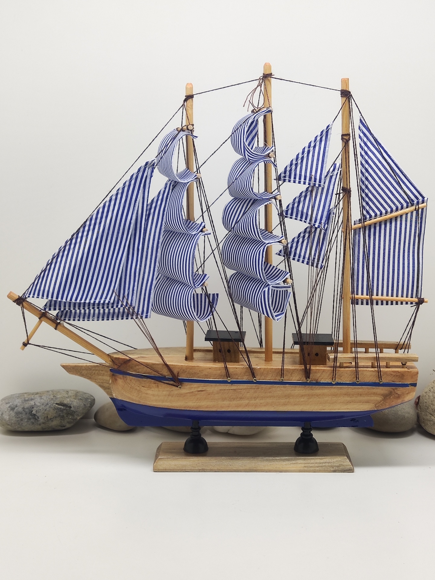 Barco de vela decorativo em madeira com velas azuis e brancas listradas