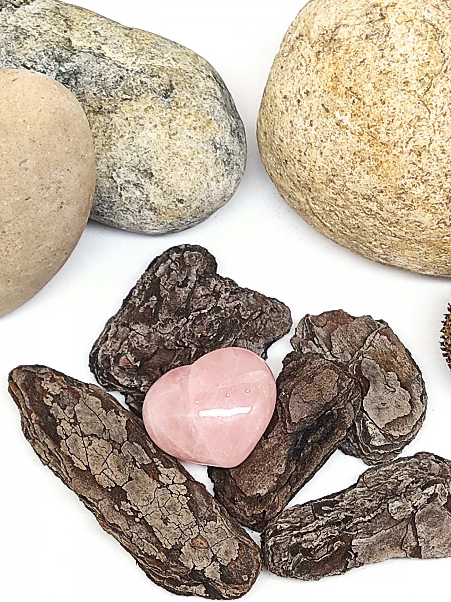 Pedras naturais variando entre cinzento, bege, castanho e uma pedra rosa em forma de coração