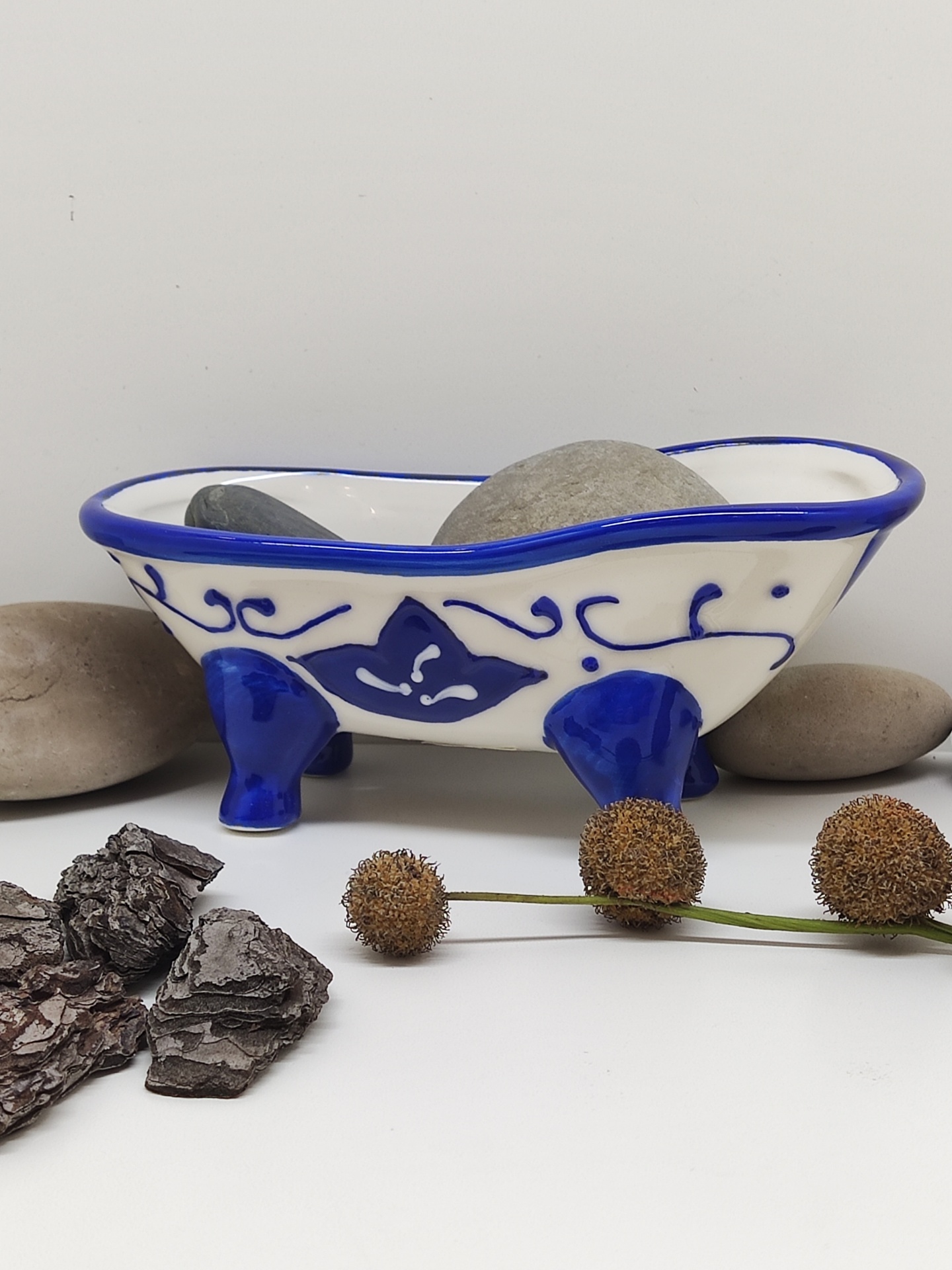 Banheira decorativa cerâmica branca e azul com pedras e elementos naturais