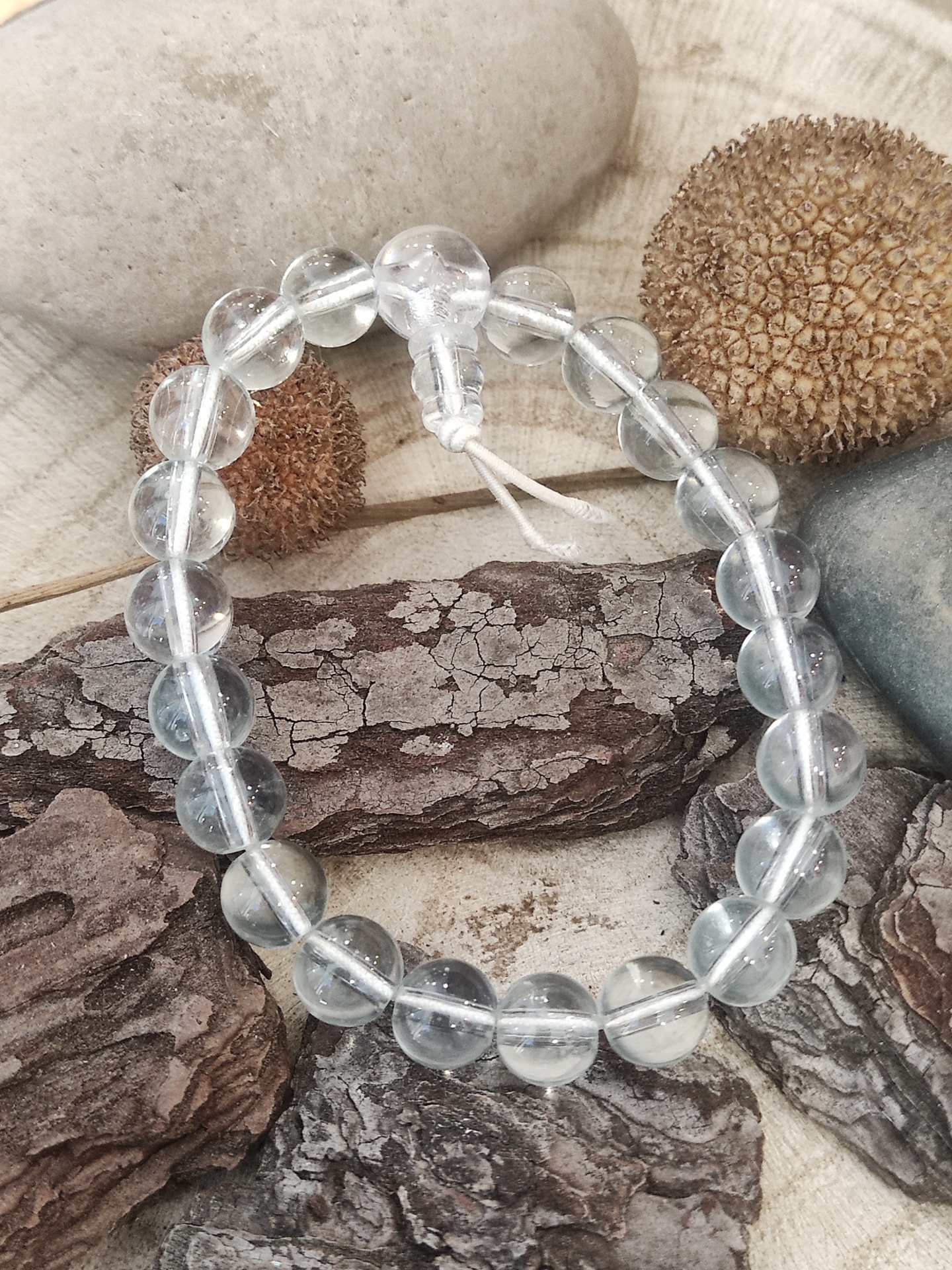 Pulseira de contas transparentes sobre pedras e superfície clara