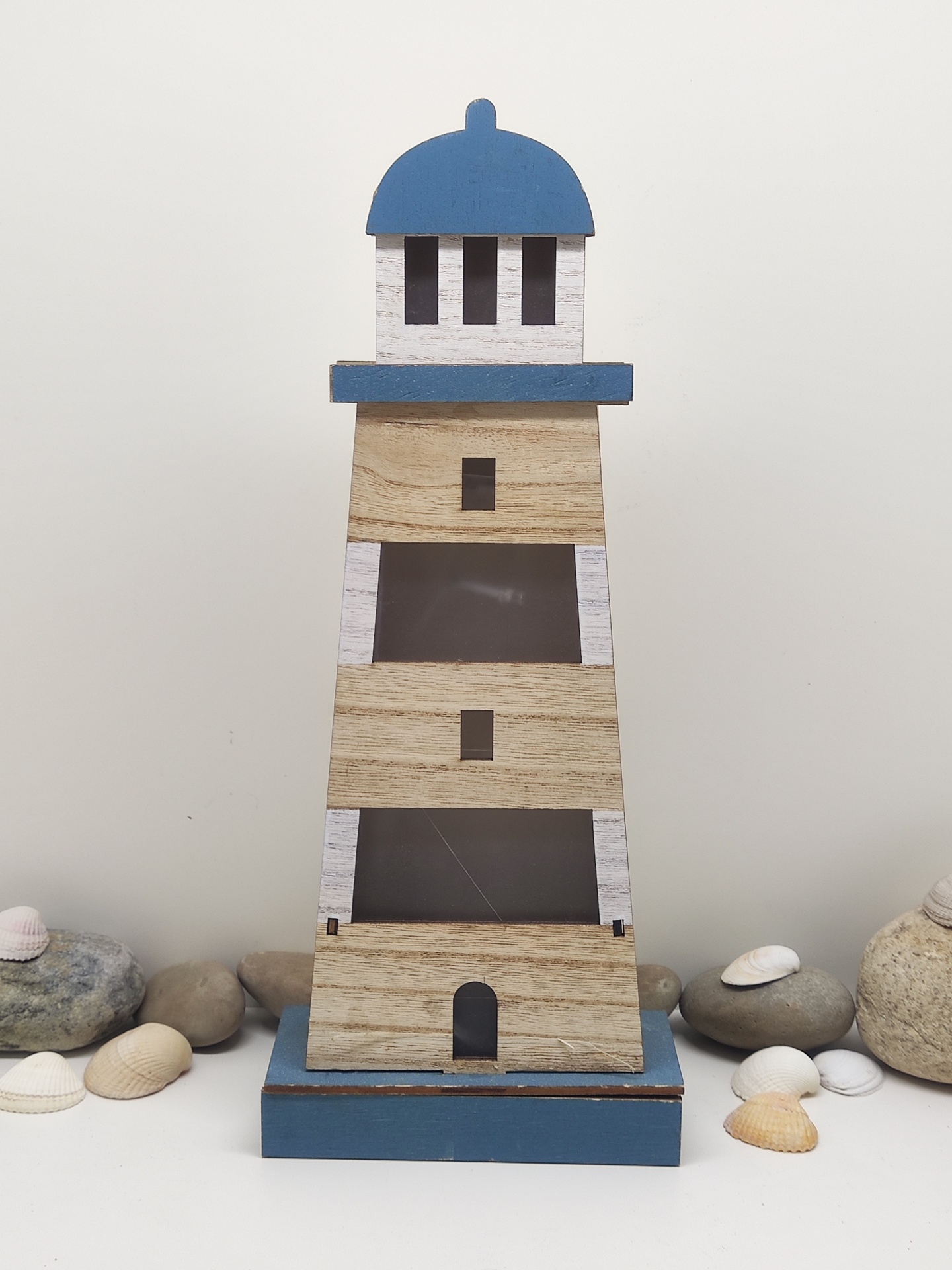 Lanterna decorativa em forma de farol azul e madeira com pedras e conchas