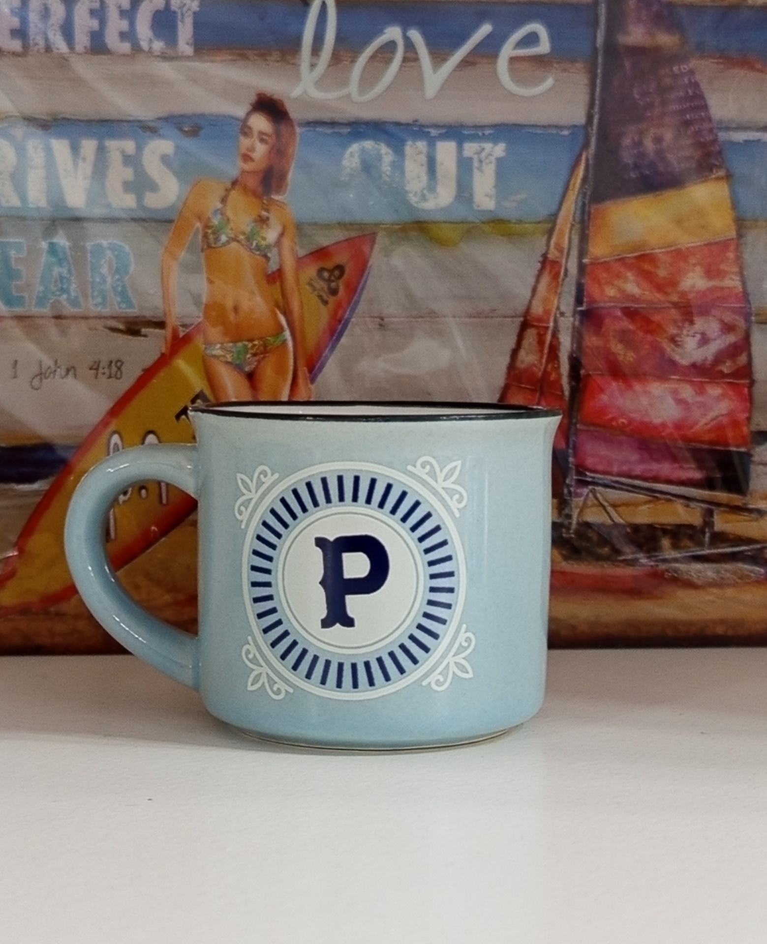 Caneca azul clara com a letra P em fundo decorativo e imagem de surf ao fundo