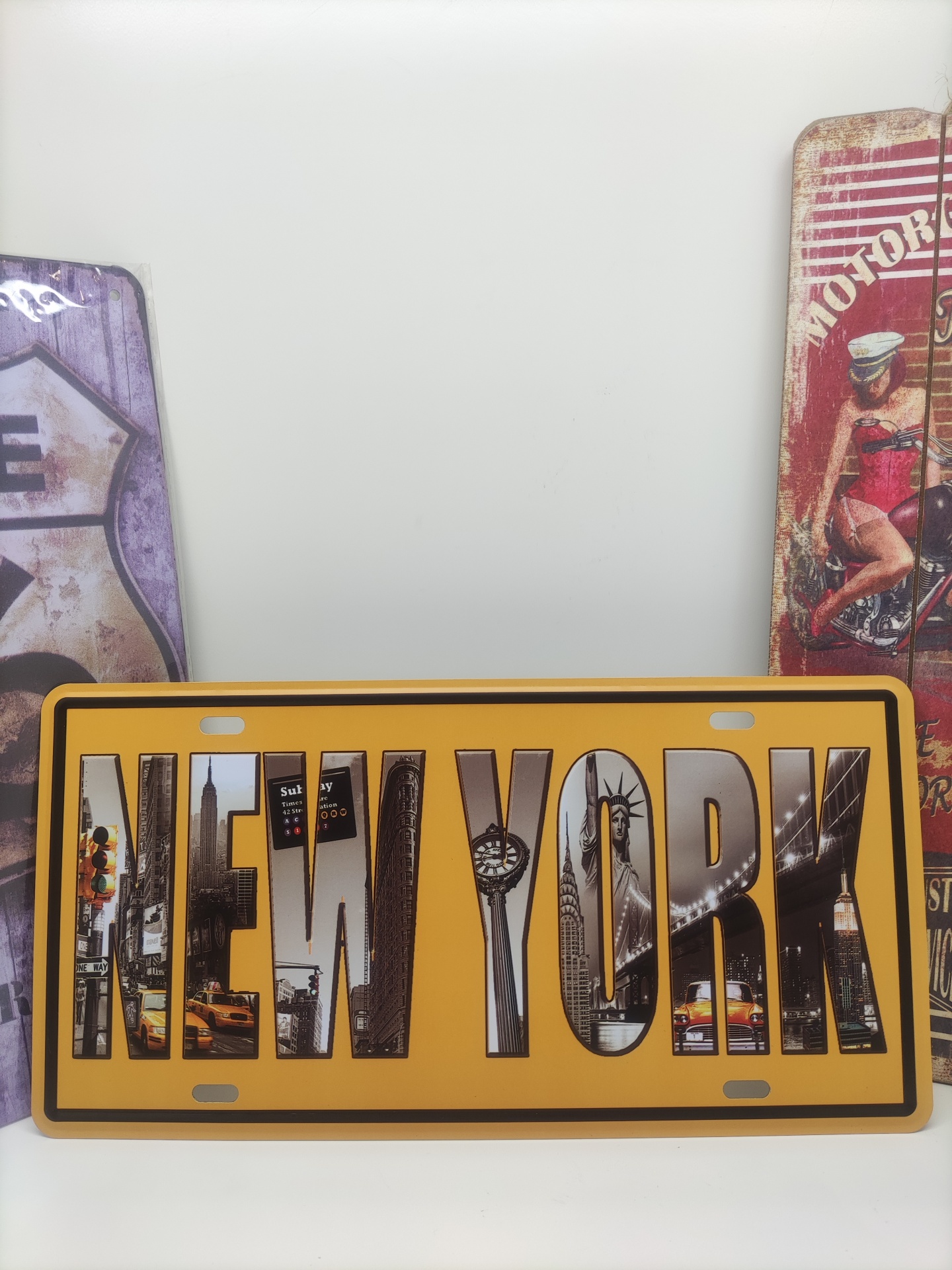 Placa decorativa amarela com a palavra NEW YORK preenchida com imagens da cidade de Nova Iorque.