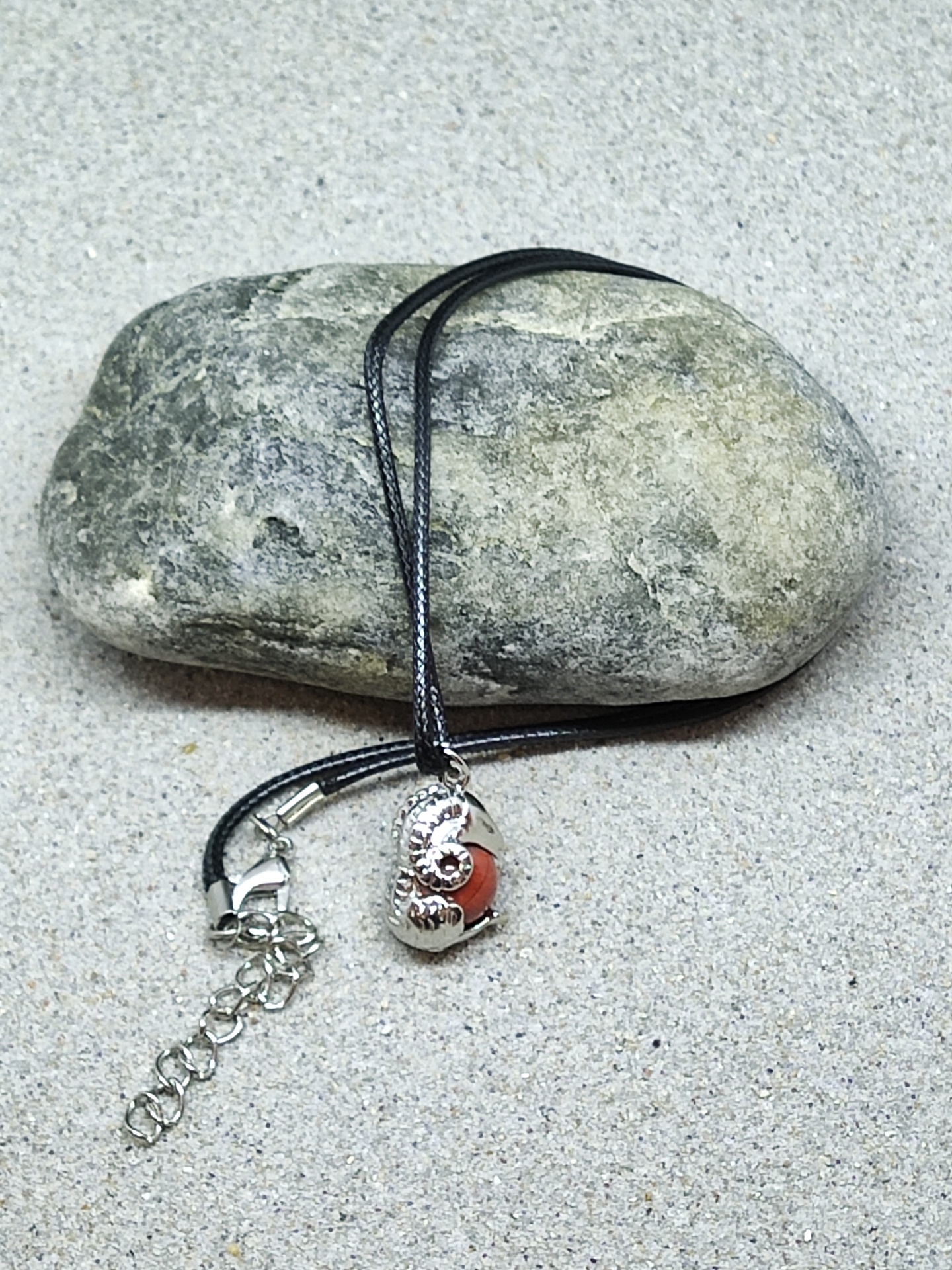 Colar com pingente amonite prateado e detalhe vermelho sobre pedra cinzenta