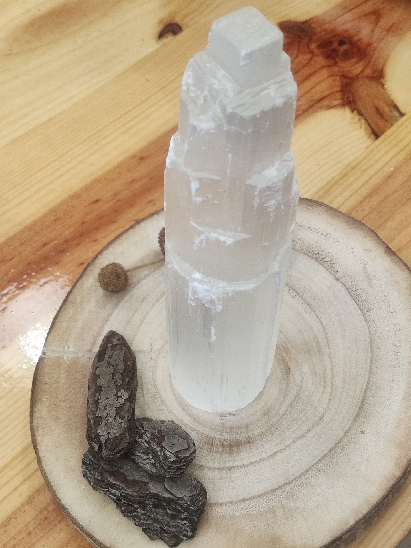 Cristal branco translúcido sobre base de madeira com dois objetos escuros ao lado