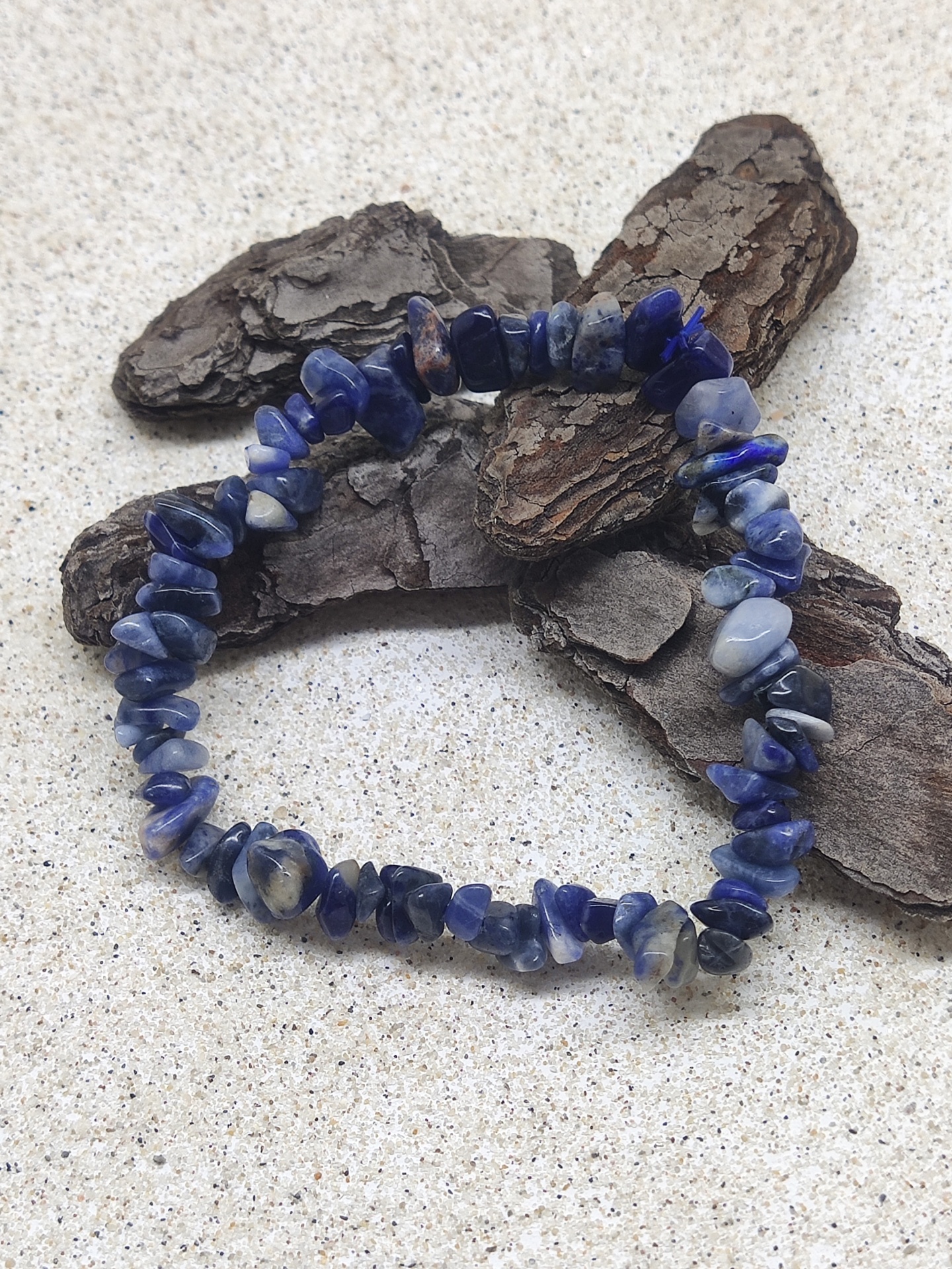 Pulseira azul e branca sobre superfície clara com casca de árvore