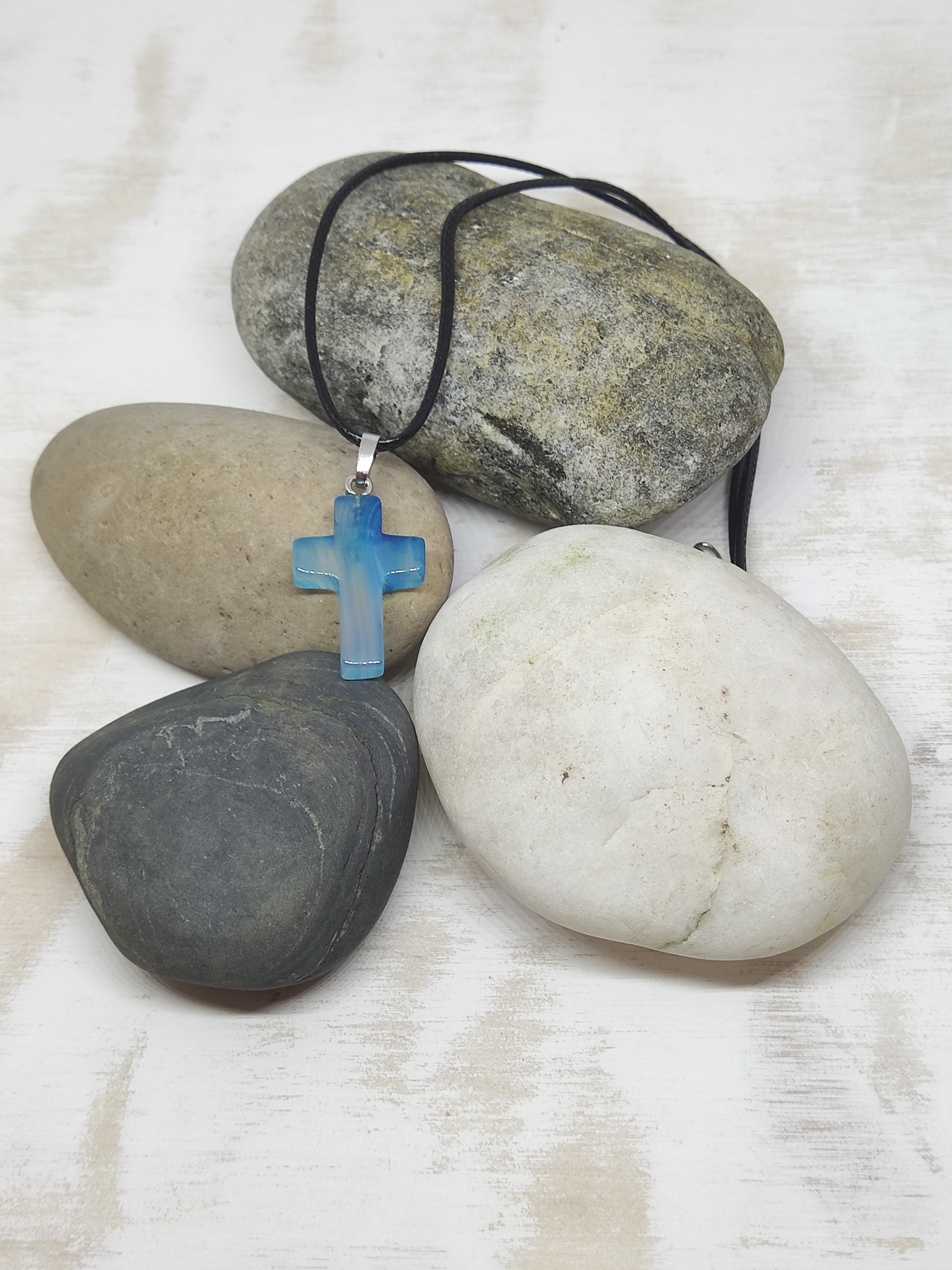 Colar com crucifixo azul em pedra pendurado sobre pedras