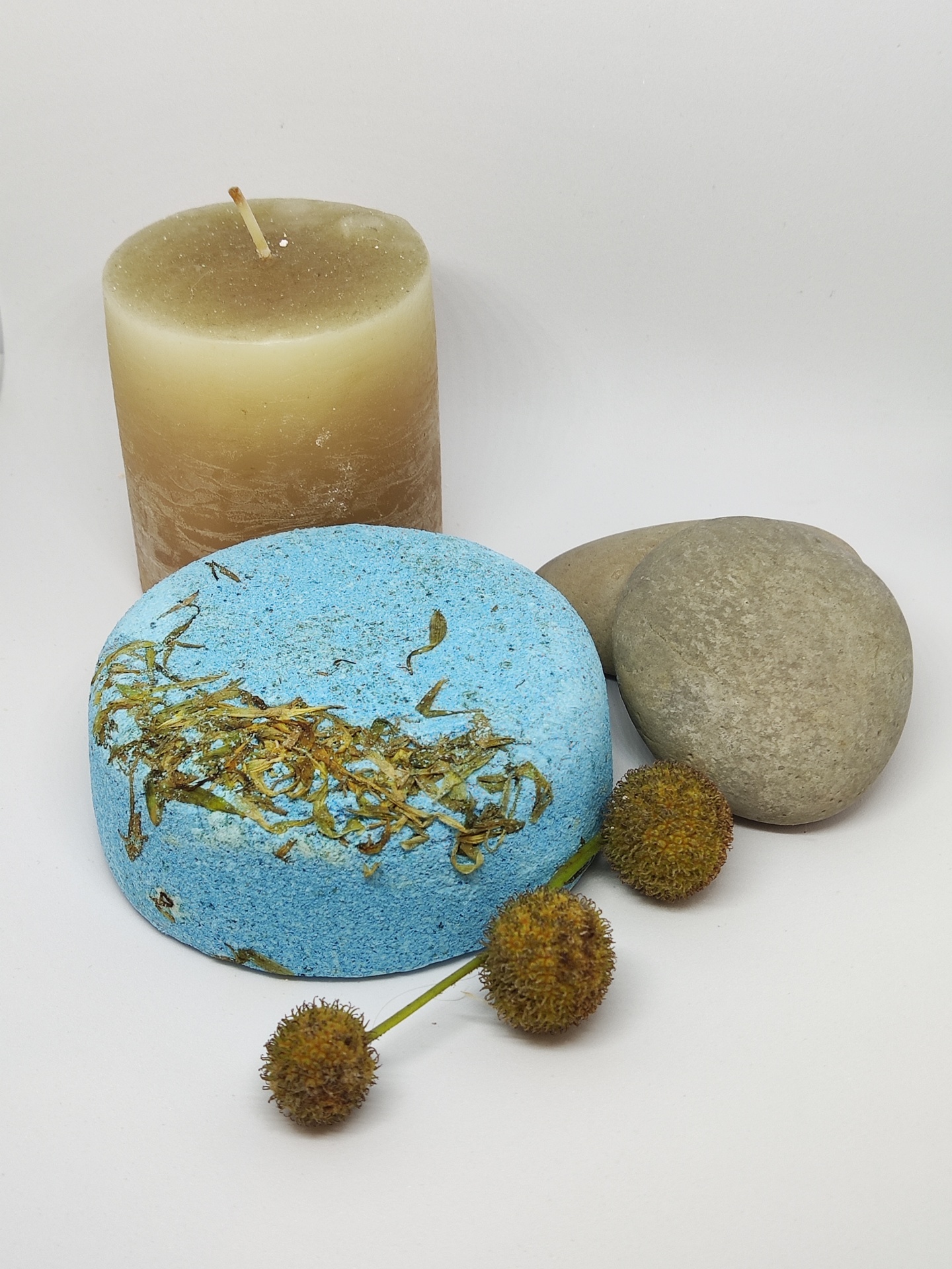 Conjunto com vela castanha, pedra cinza, bola azul com ervas e flores secas.