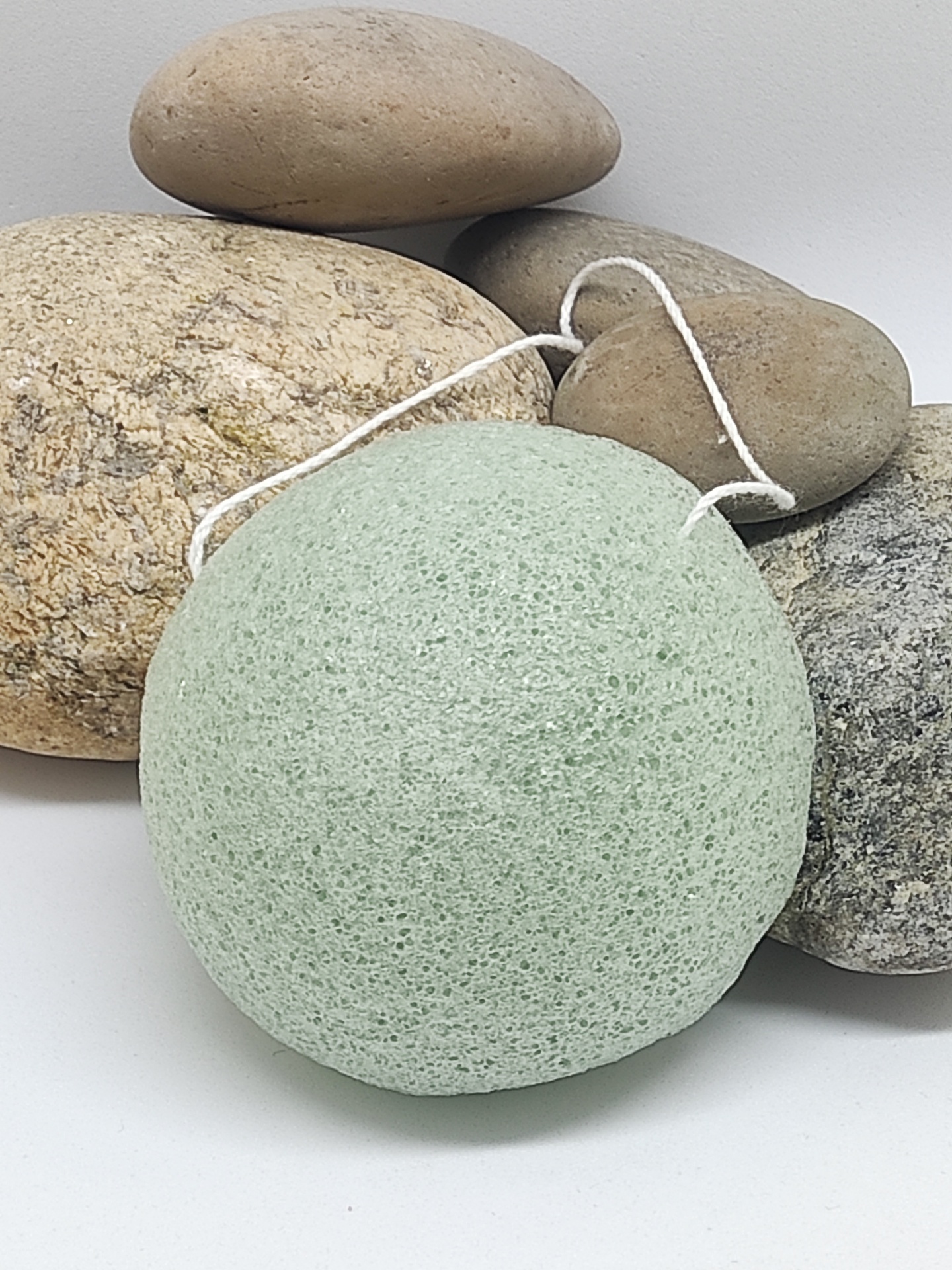 Esponja verde com cordão sobre pedras castanhas e cinzentas