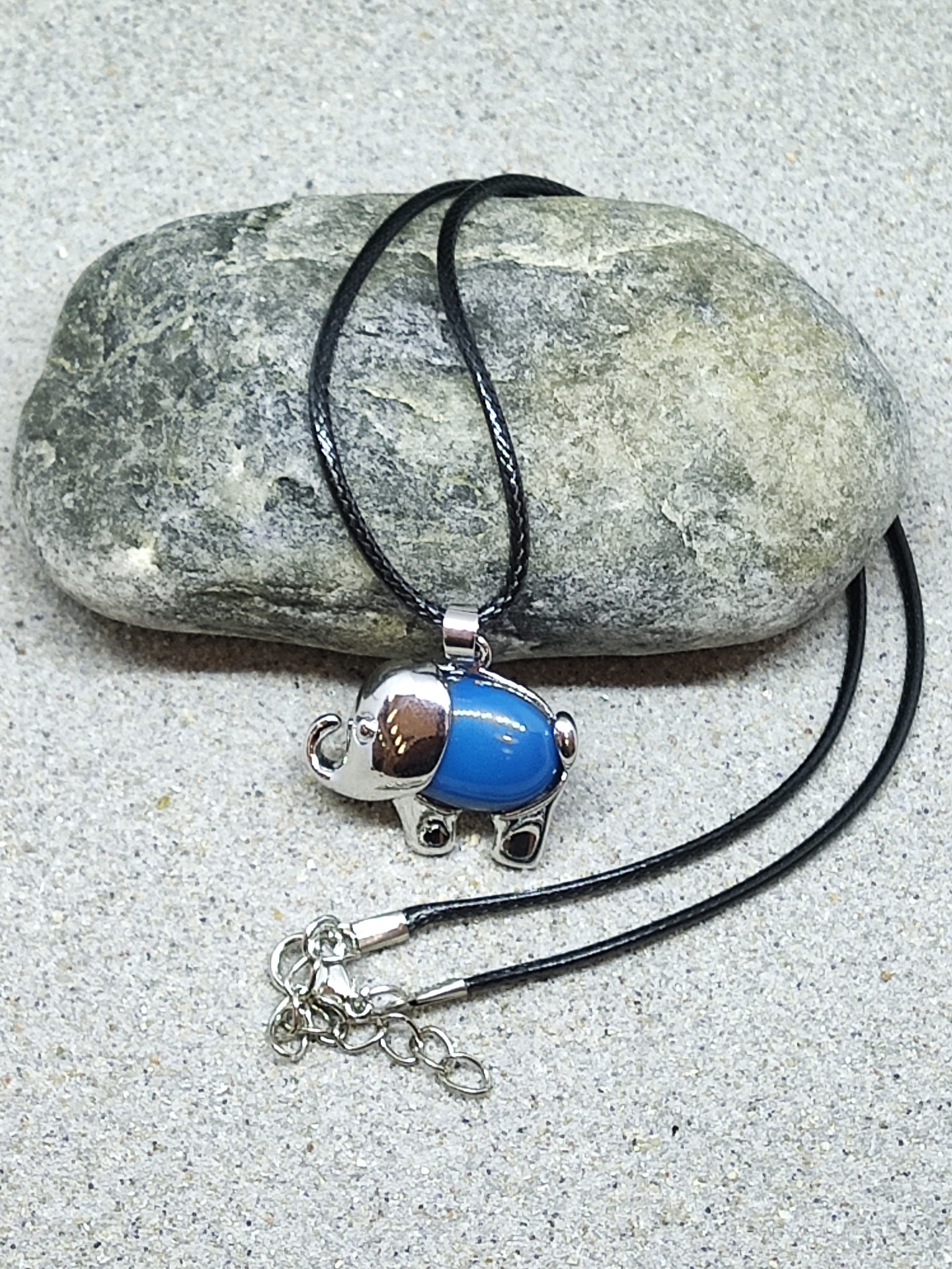 Colar preto com pendente elefante prateado e azul sobre pedra cinza