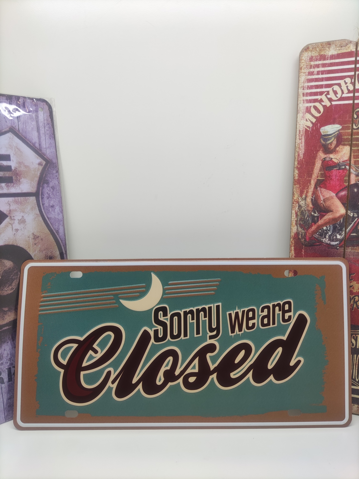 Placa metálica verde com texto 'Sorry we are Closed' em castanho e branco