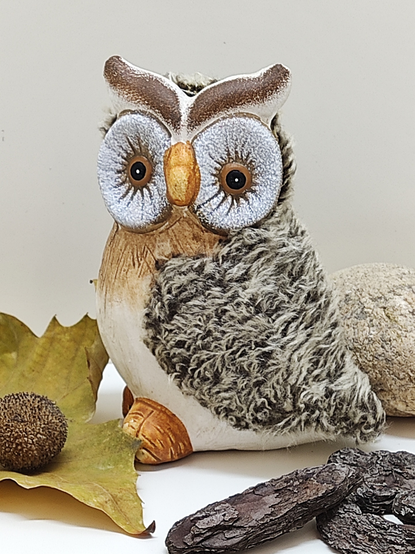 Estátua decorativa de coruja com asas cinzentas texturizadas e olhos grandes em fundo branco