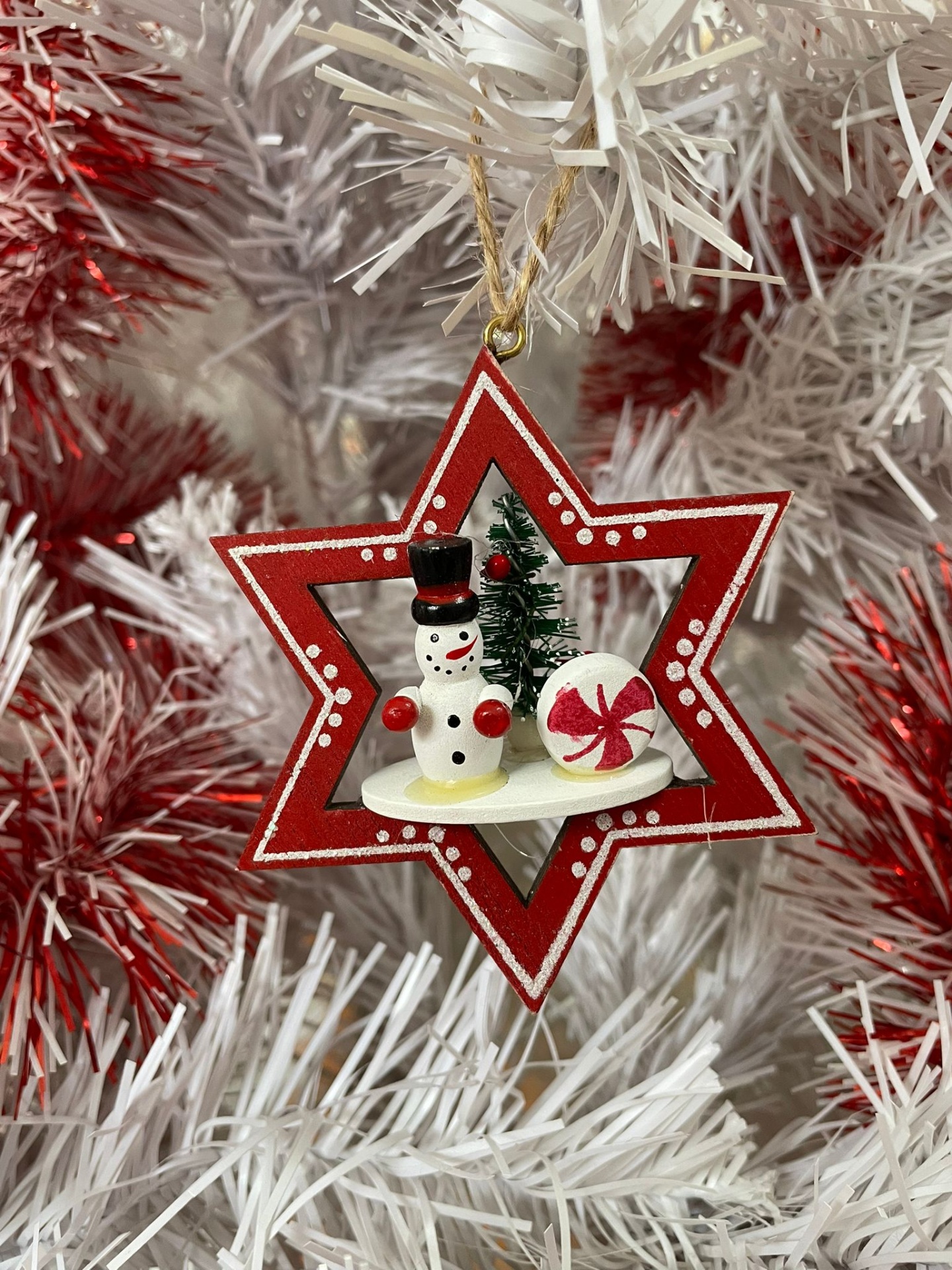 Enfeite de Natal estrela vermelha com boneco de neve e árvore na árvore branca