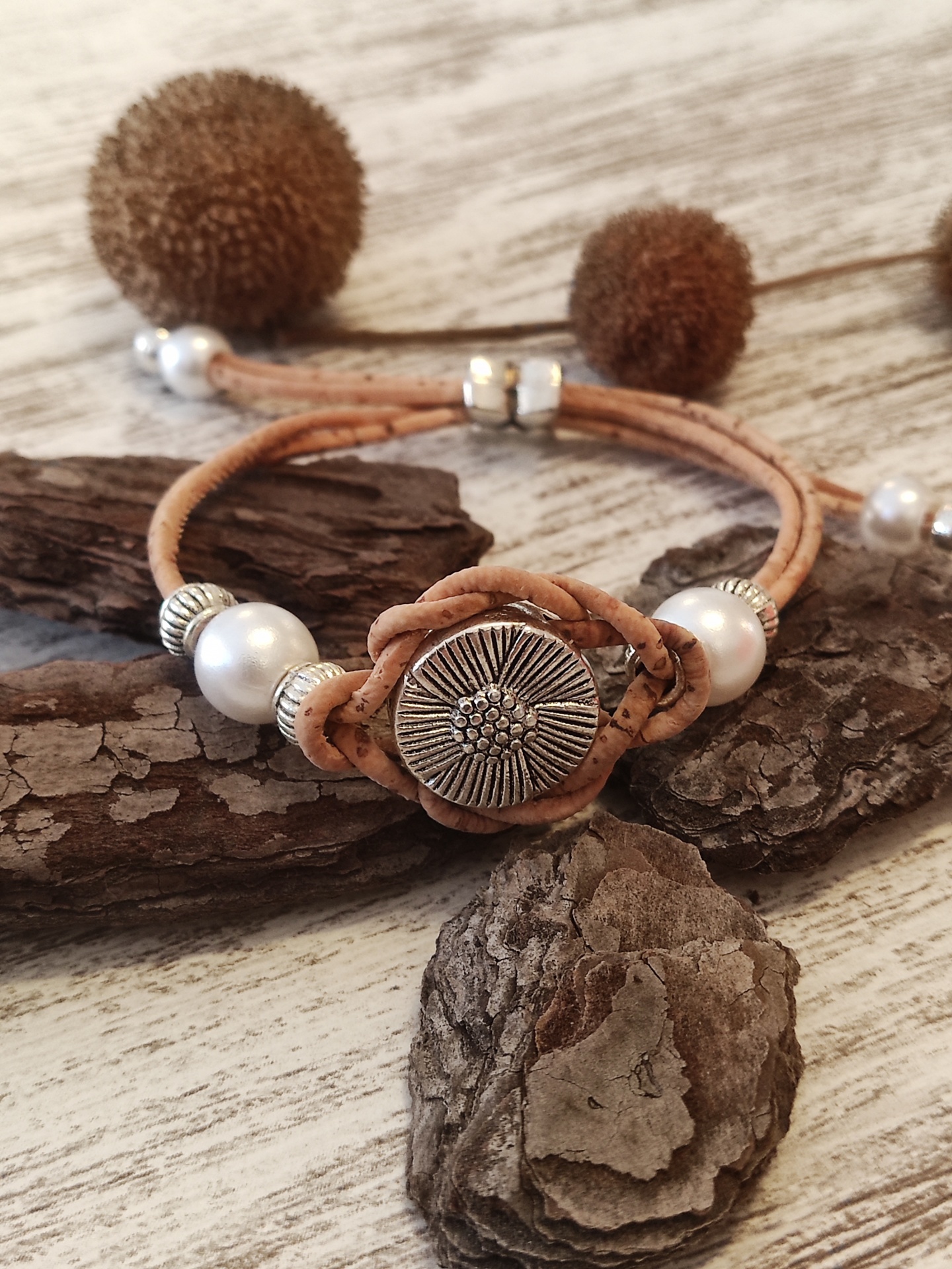 Pulseira de cortiça mel com pérolas e fecho prateado sobre fundo de madeira