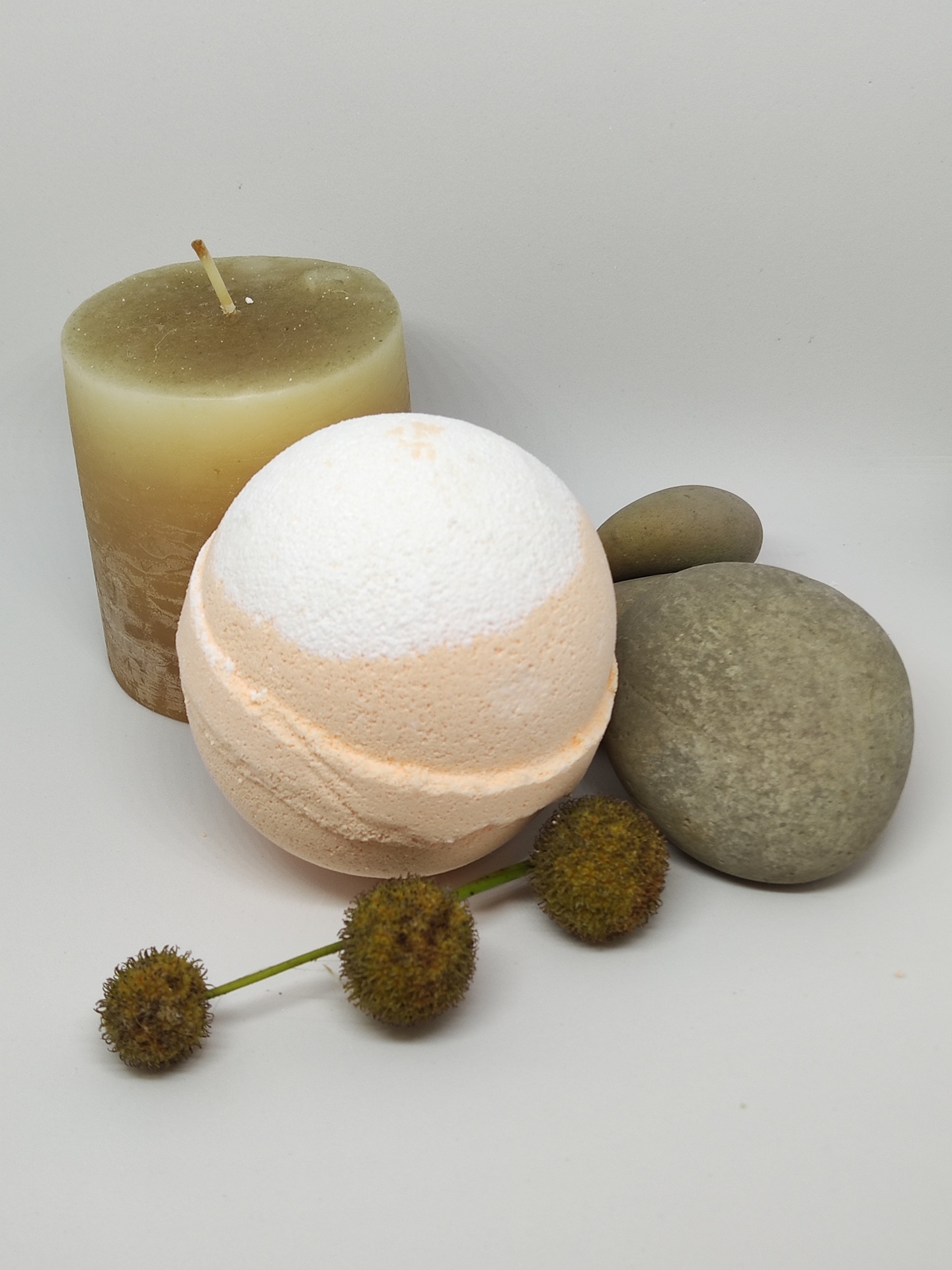 Vela castanha, bola de banho branca e salmão, pedras cinzentas e flores secas