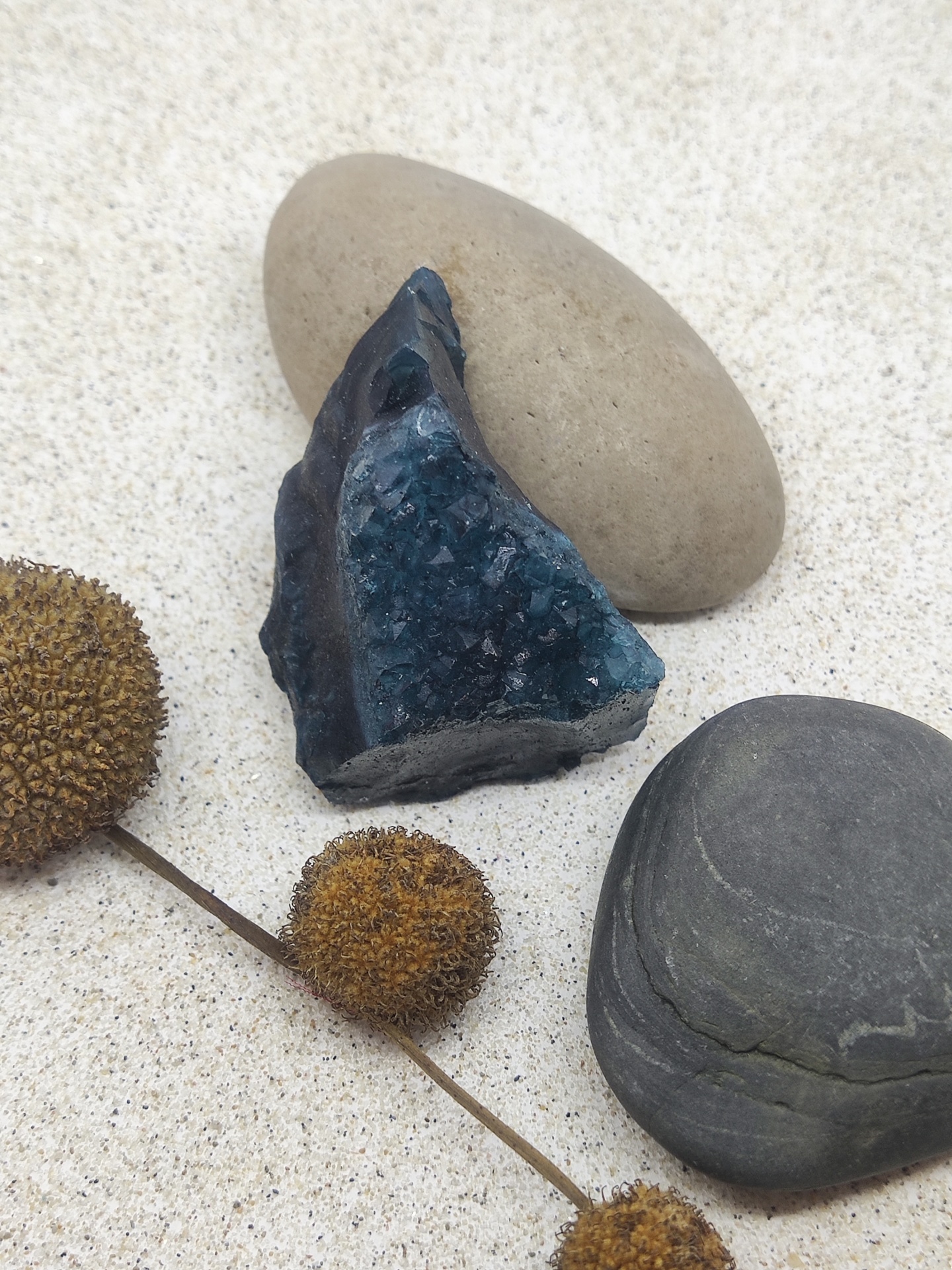 Três pedras e ramo seco em areia clara