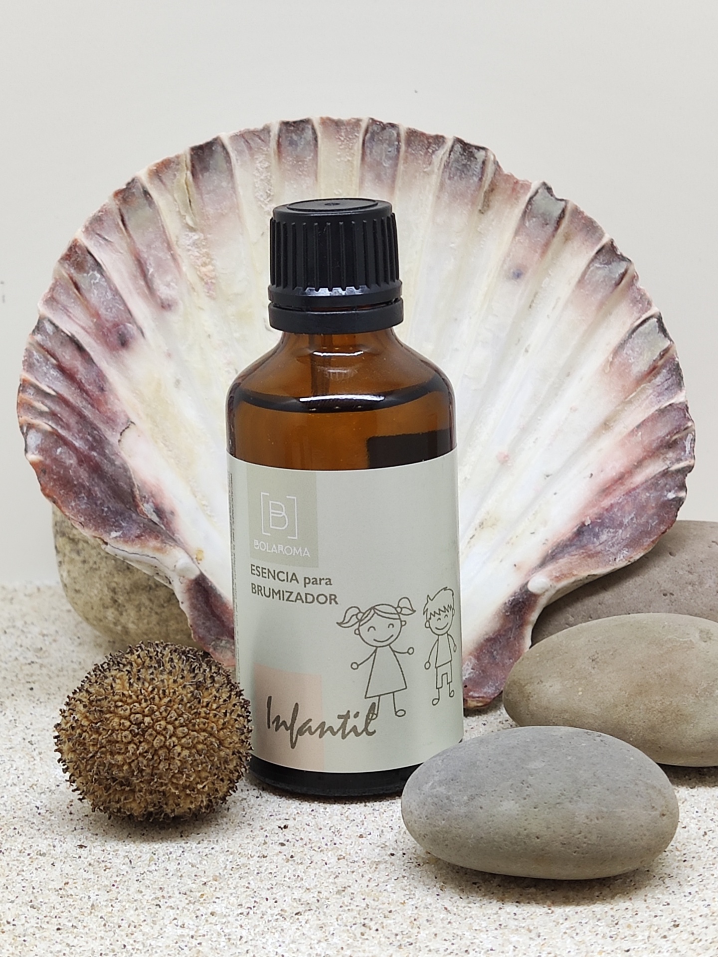 Frasco âmbar com rótulo infantil em areia com concha e pedras