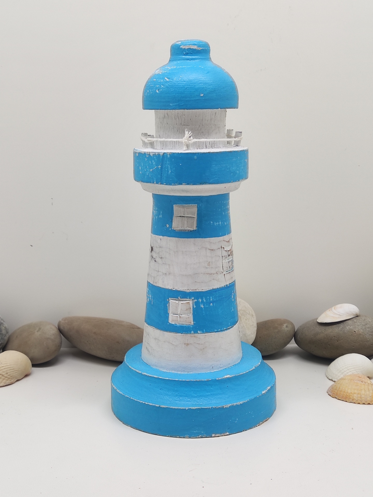 Miniatura decorativa de farol azul e branco em madeira com pedras e conchas