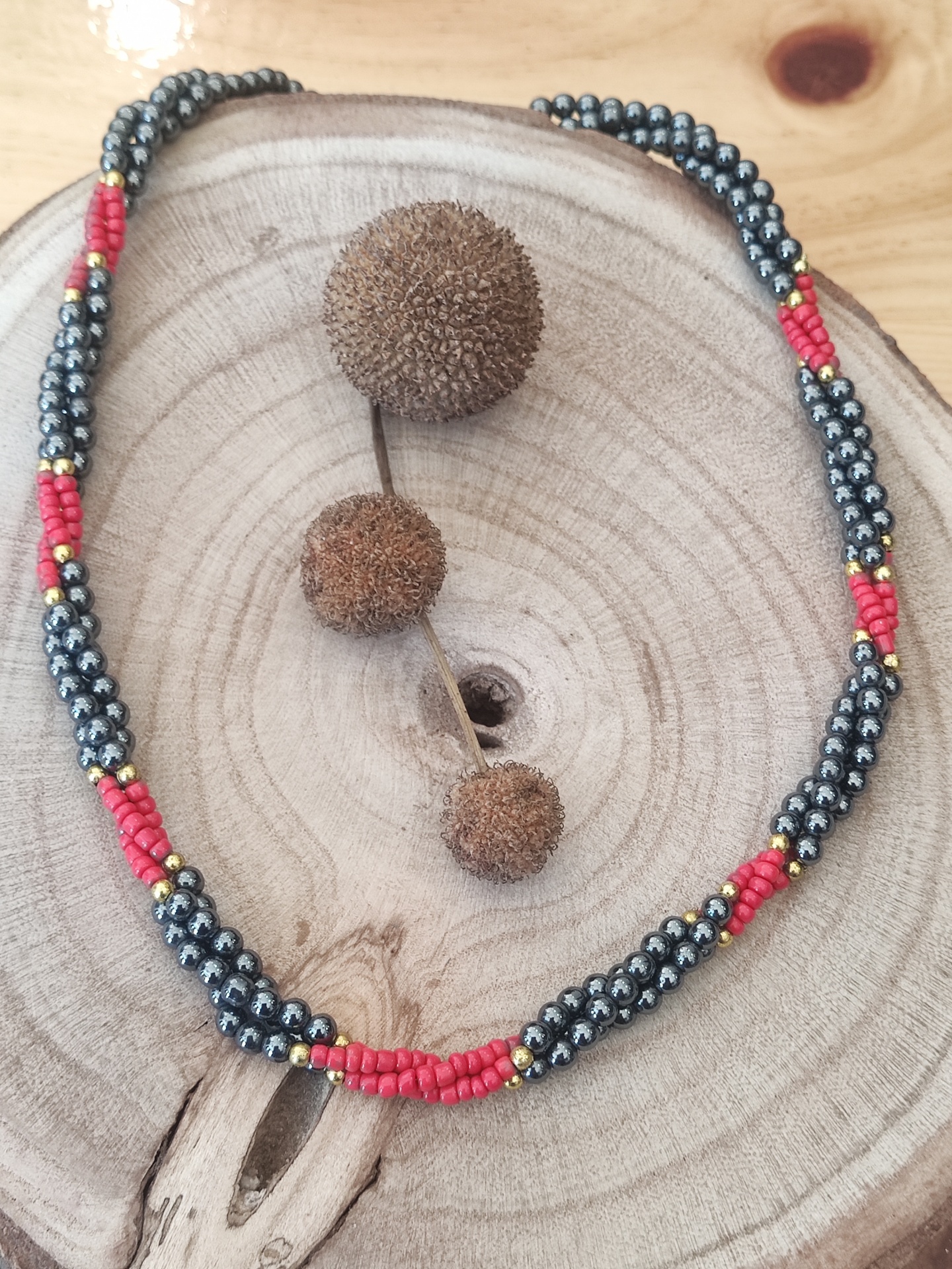 Colar de contas coloridas sobre madeira clara com frutos secos