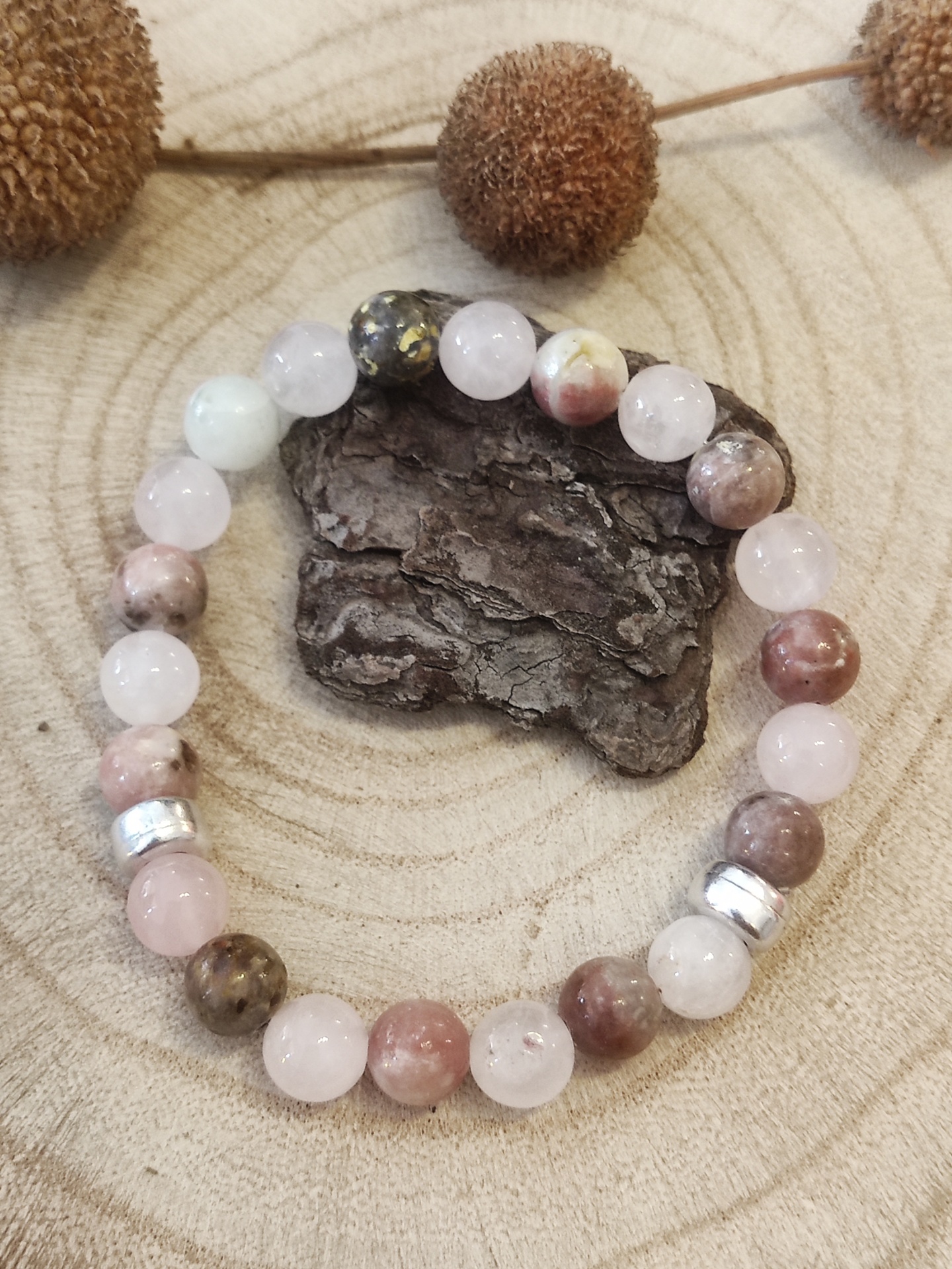 Pulseira de contas coloridas em torno de uma peça de madeira sobre superfície de madeira circular