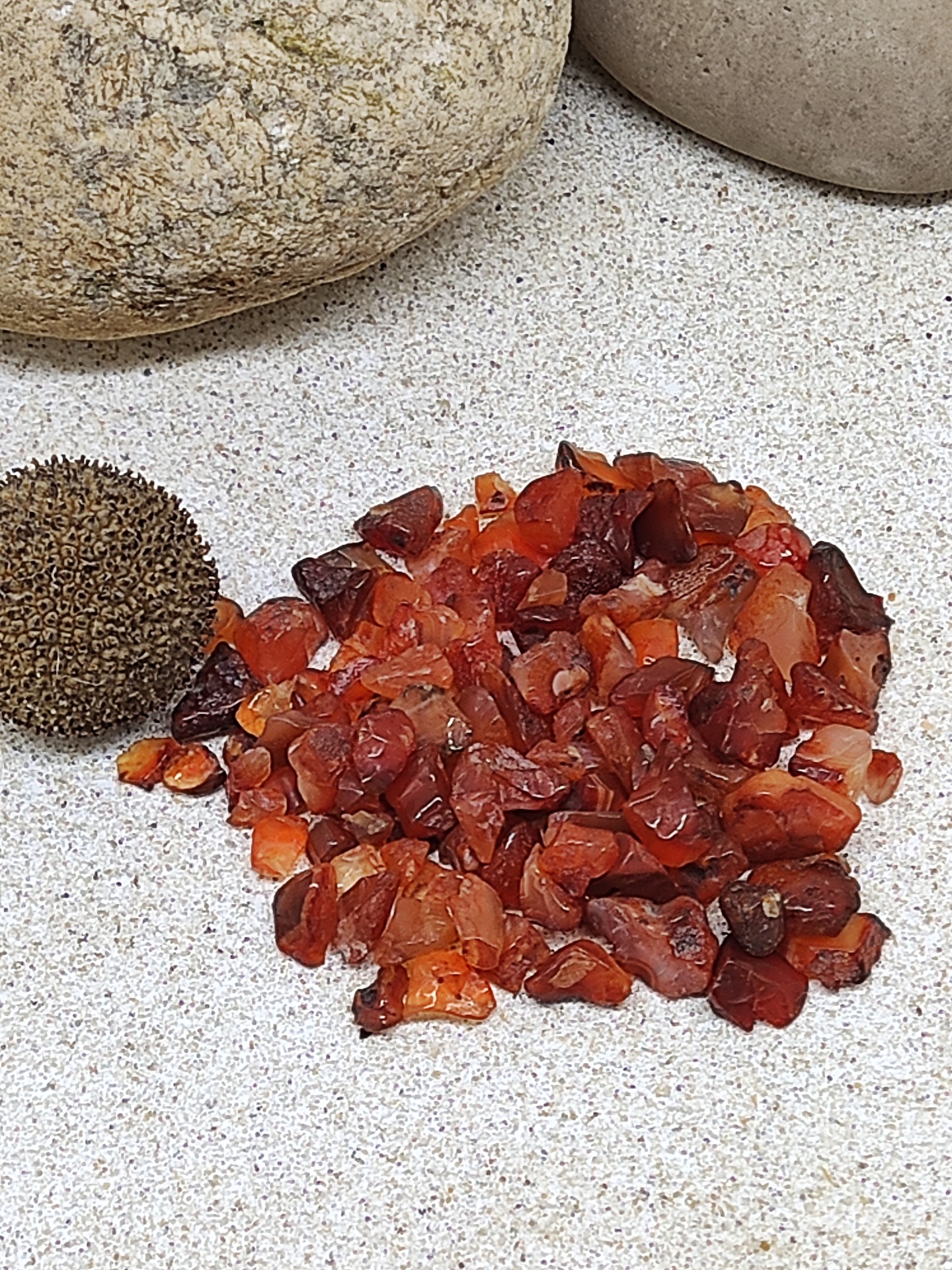 Pedras pequenas laranja e vermelhas com pedras maiores e uma esfera texturada